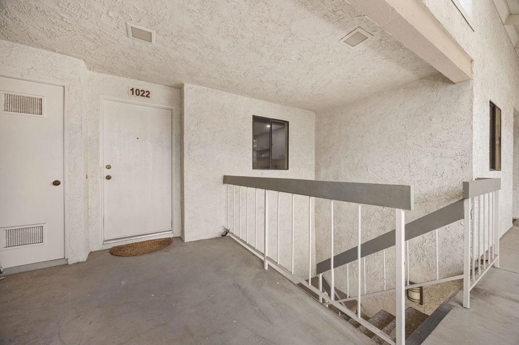 Unit 1022’s exterior entry landing with a white door and stair railing.