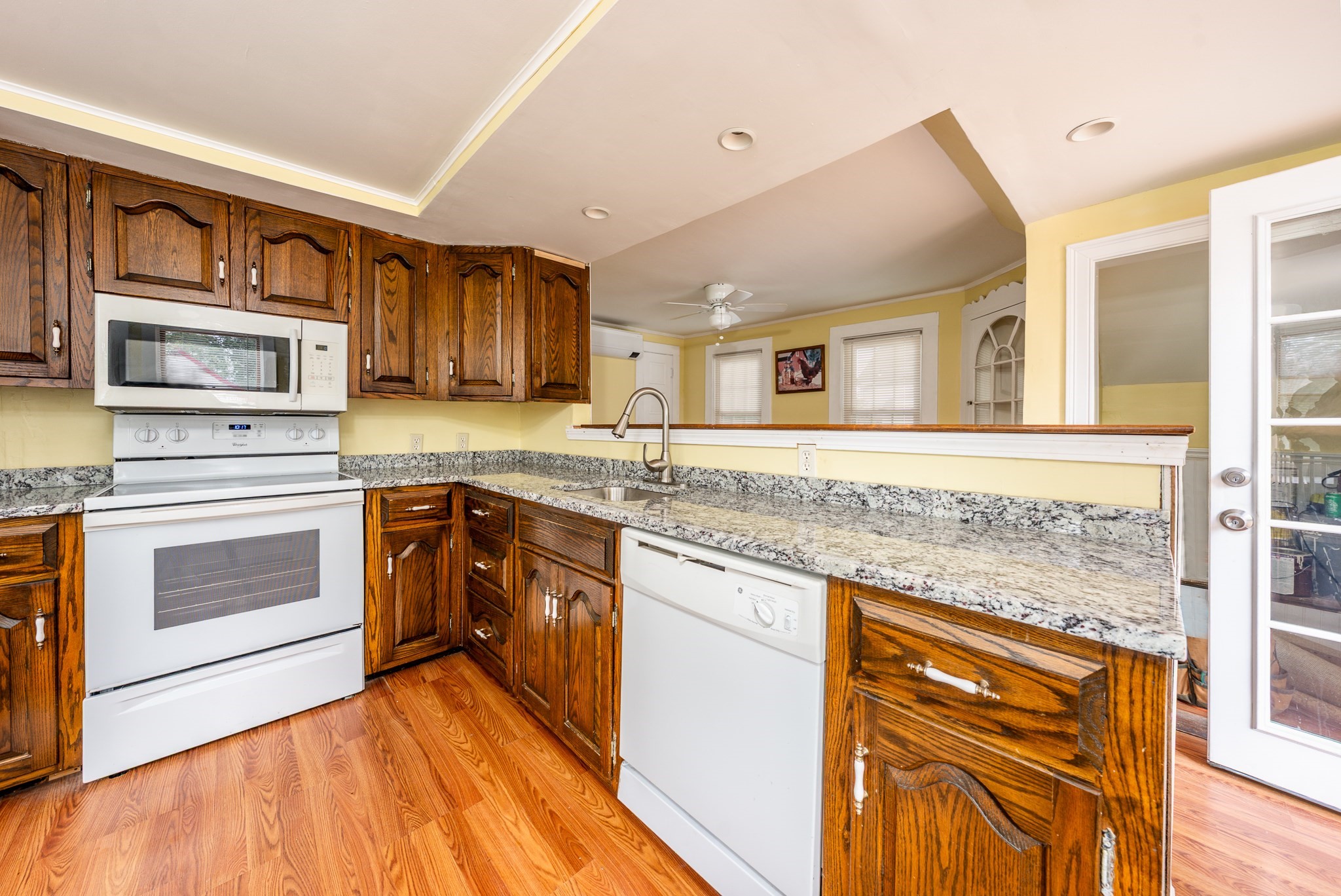 Kitchen with dark wood cabinets, granite counters, white appliances, and a breakfast bar.