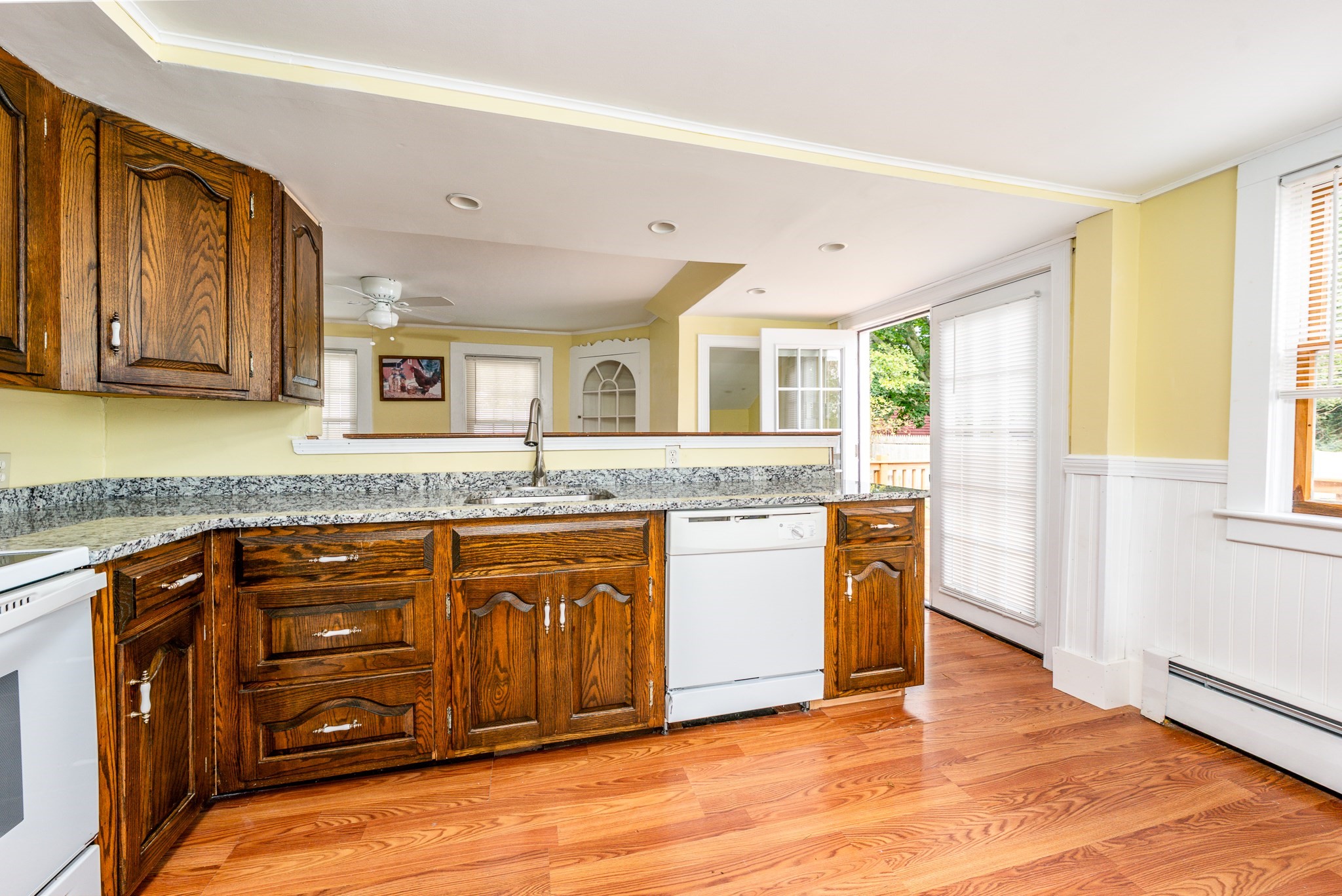 Kitchen with dark wood cabinets, granite counters, hardwood floors, and an open glass door to the deck.