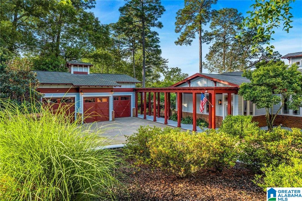 Home with red garage doors and a covered drive framed by landscaped greenery.