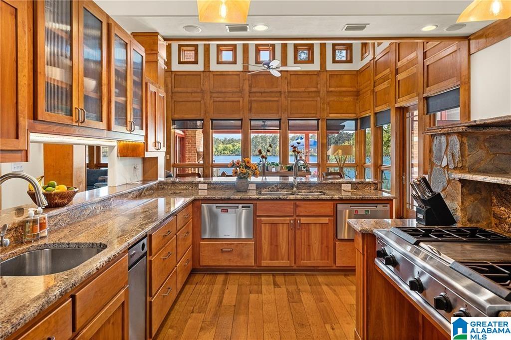 Wood-paneled kitchen with granite counters, stainless steel appliances, and water visible through the windows.