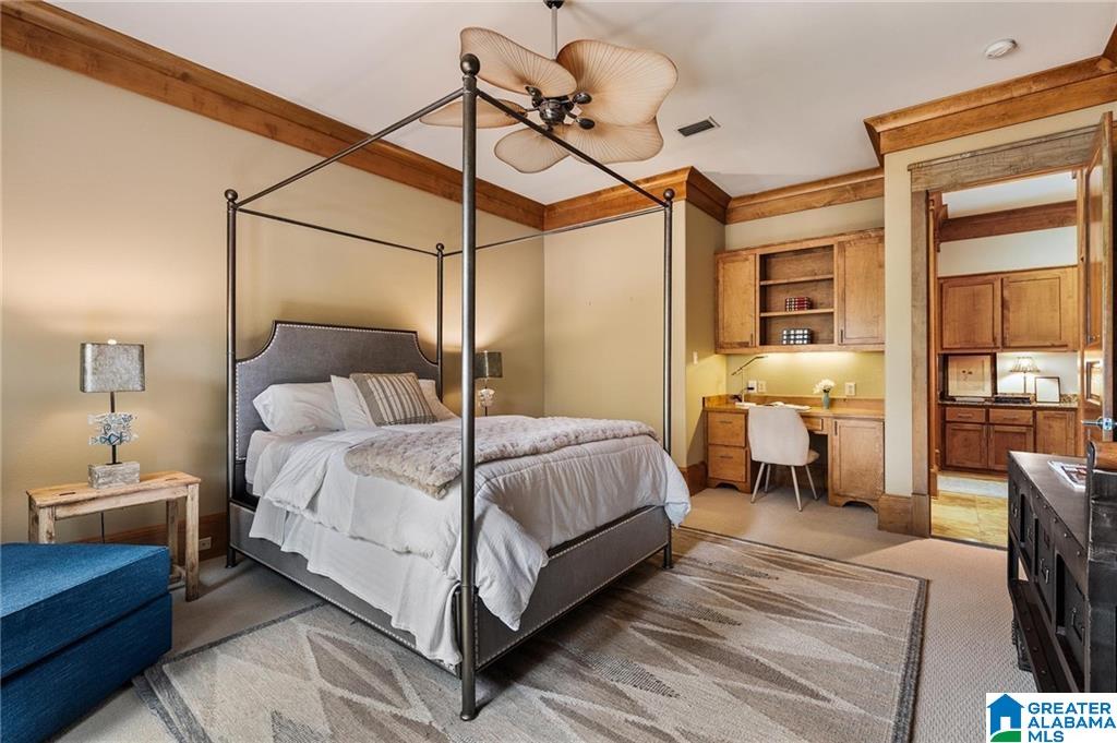 Bedroom with a dark four-poster bed, white bedding, and a built-in wooden desk nook.