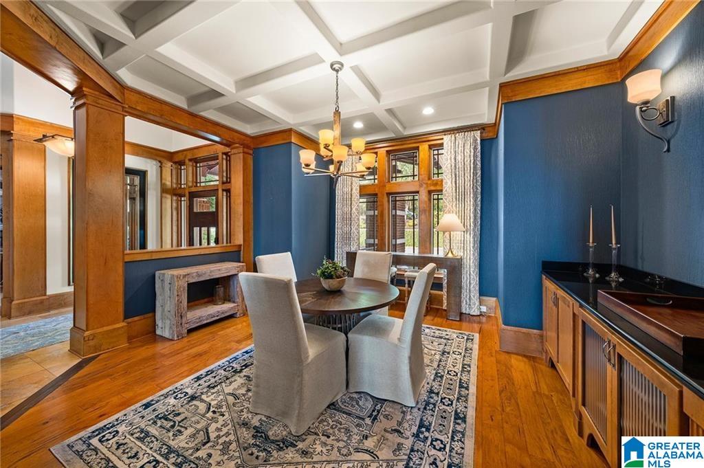 Dining room with a round table, blue walls, wood trim, and a white coffered ceiling.