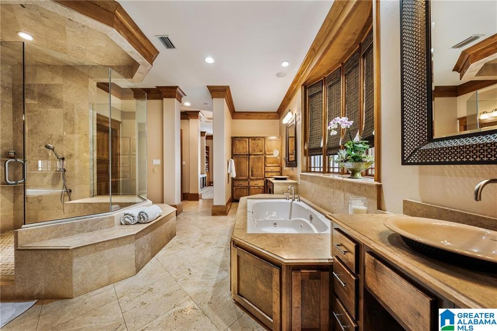 Spacious bathroom with a stone walk-in shower, jetted tub, and extensive wood cabinetry.