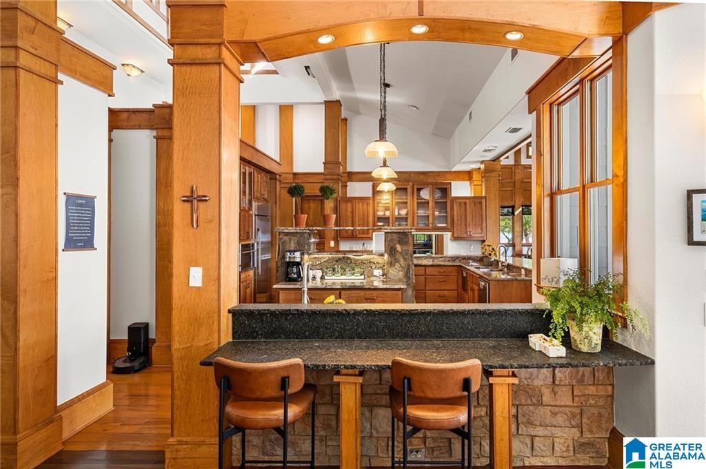 Kitchen with wood cabinetry, exposed beams, and a granite breakfast bar with two stools.