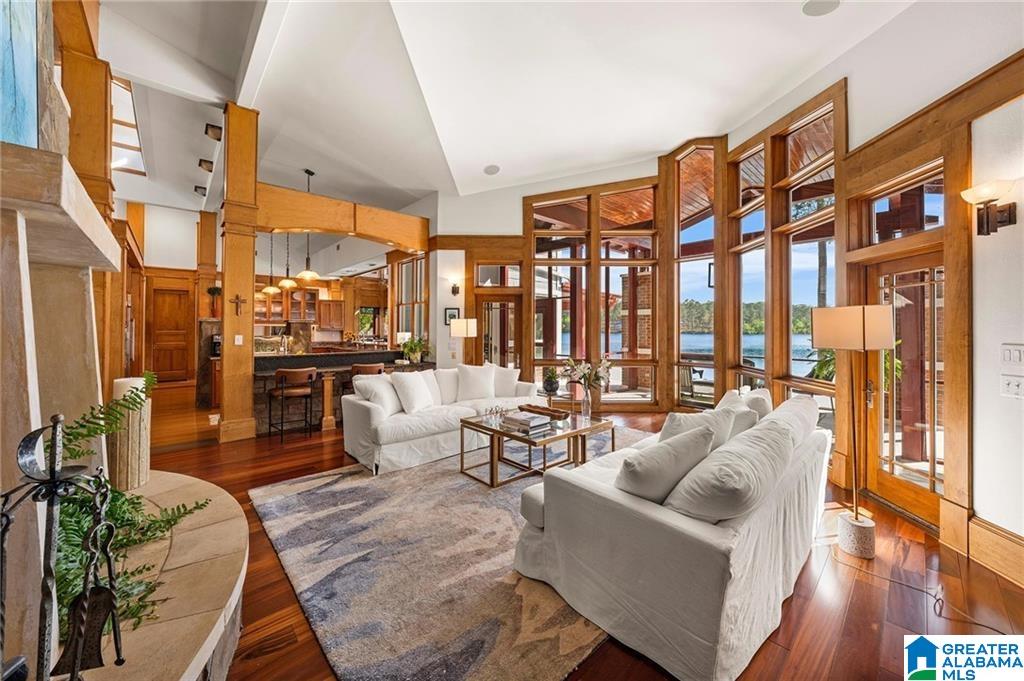 Living room with white sofas, vaulted ceiling, and tall windows overlooking the water.