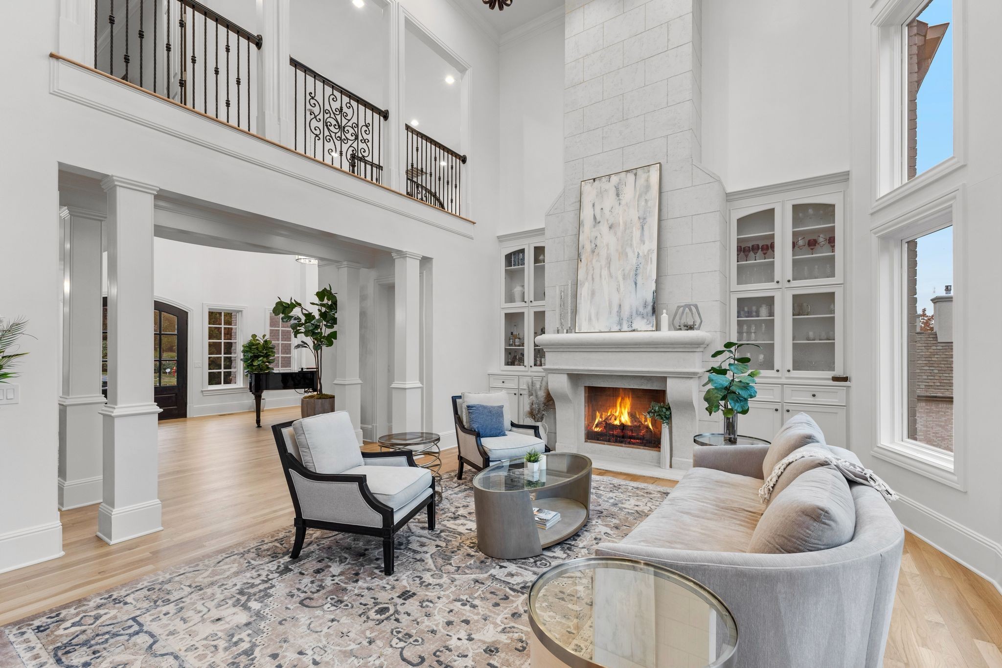Double-height living room with a stone fireplace, built-in cabinets, and an upstairs balcony.