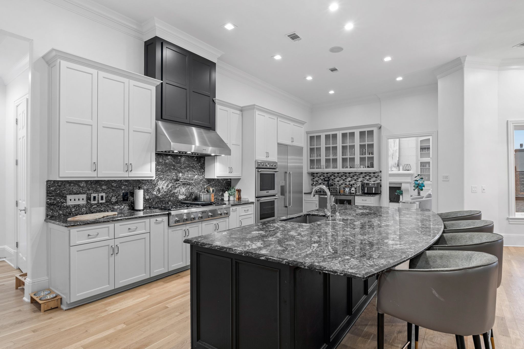 Kitchen with white cabinets, dark stone counters, stainless appliances, and a large island with bar stools.