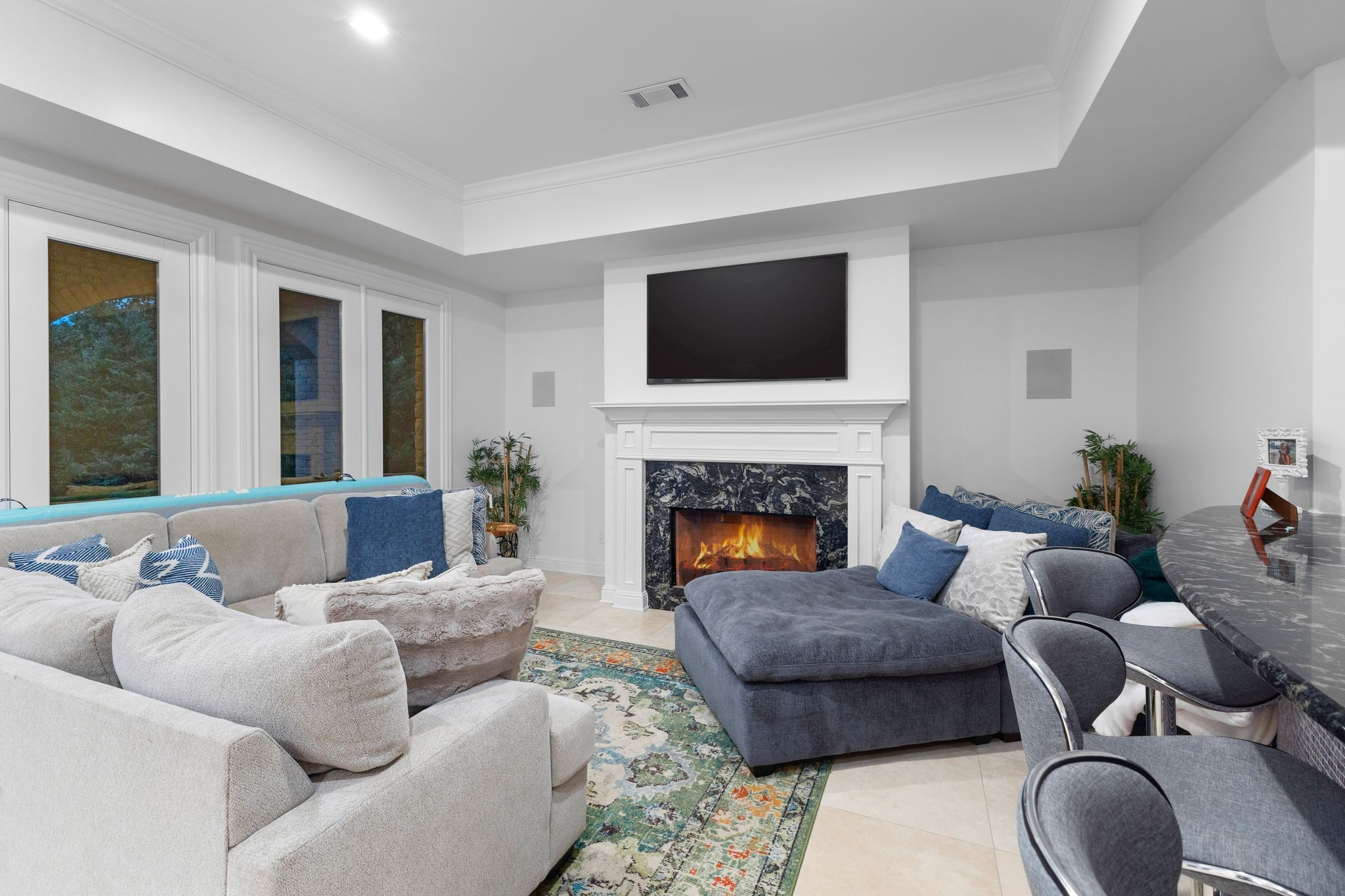 Living room with a marble fireplace, mounted television, and blue and cream sectional sofas.