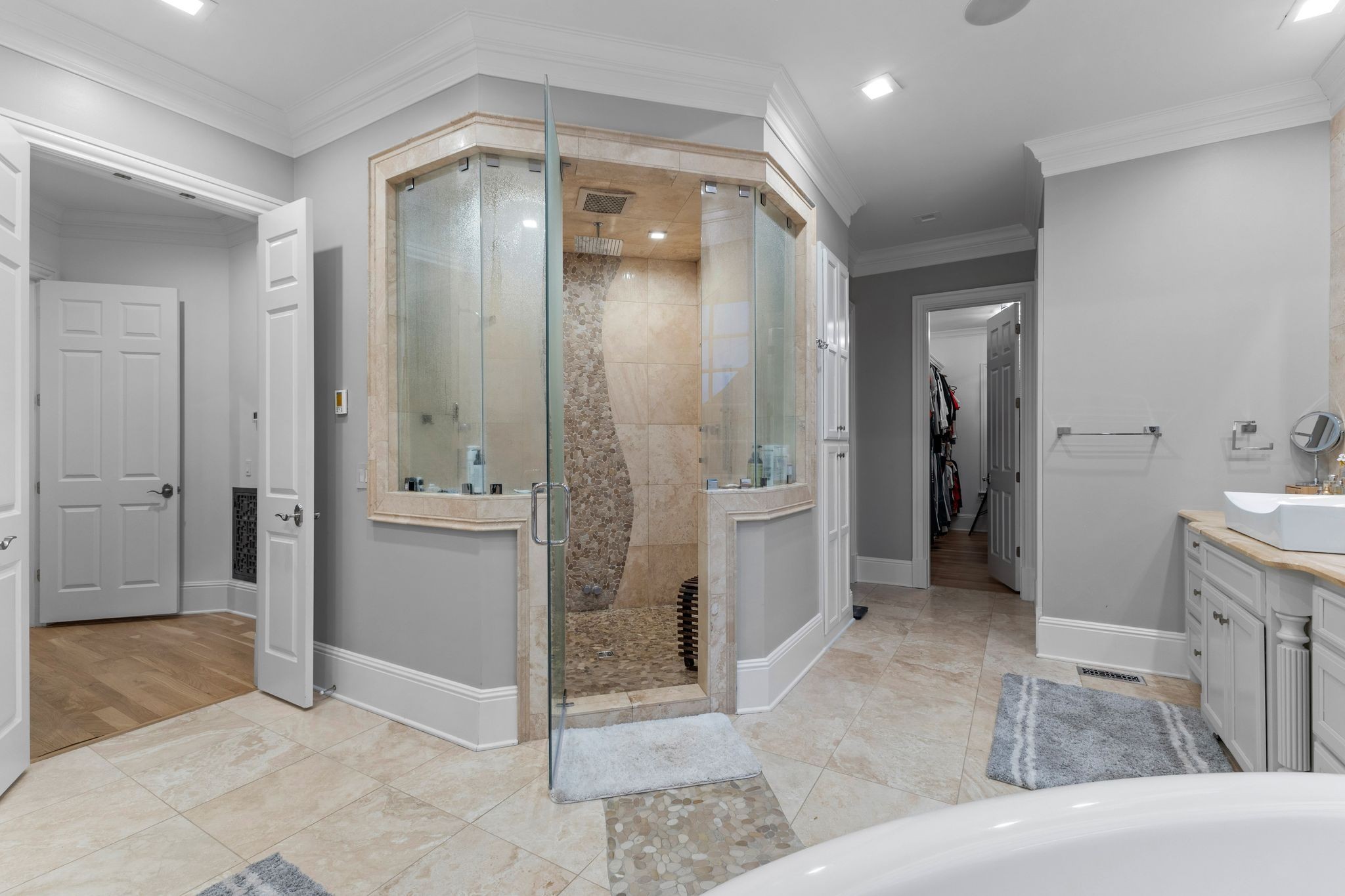 Bathroom with a glass corner shower, pebble tile accent, vessel sink, and soaking tub.