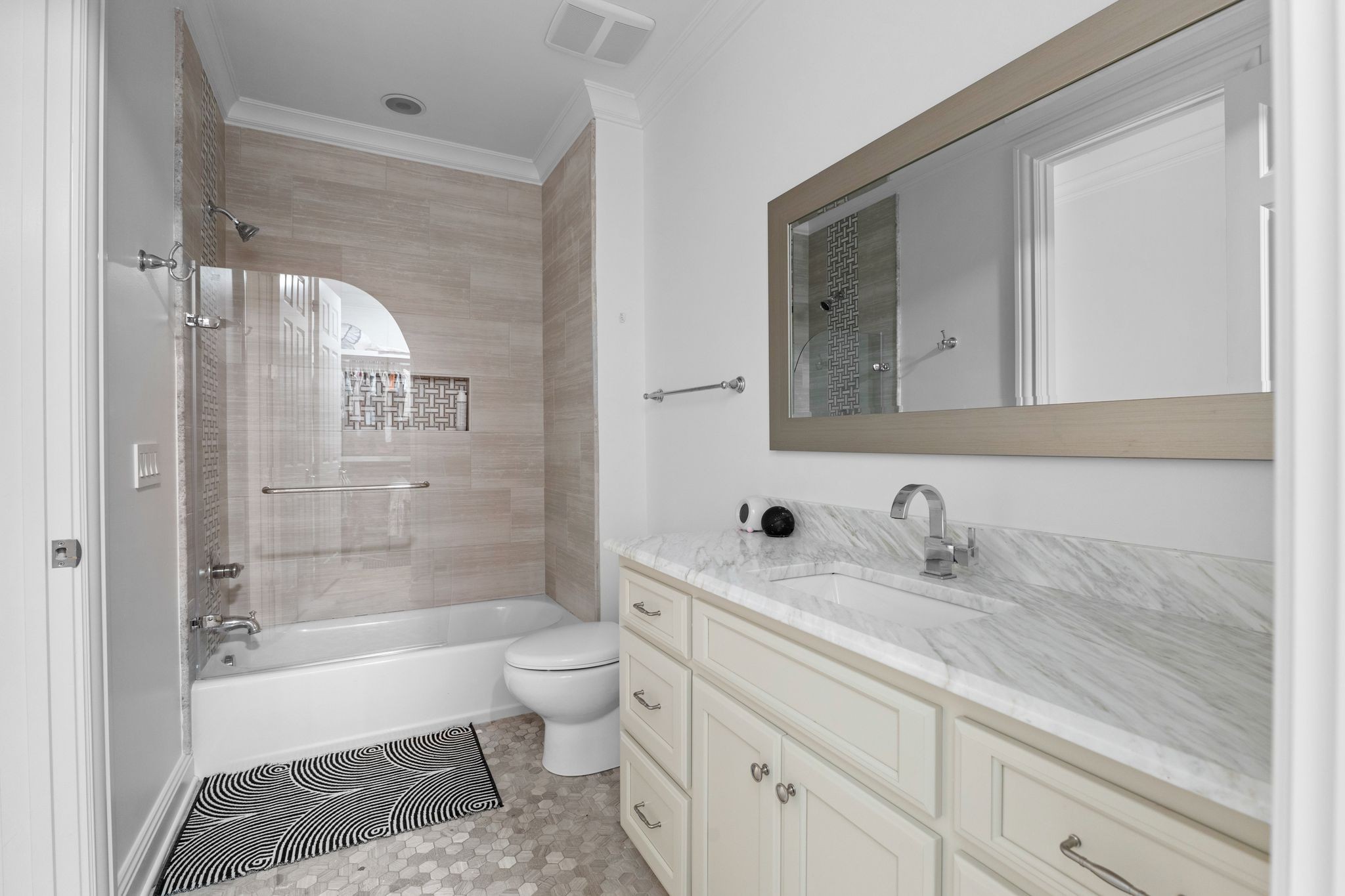 Bathroom with a glass shower enclosure, beige tile, and a marble-look vanity.