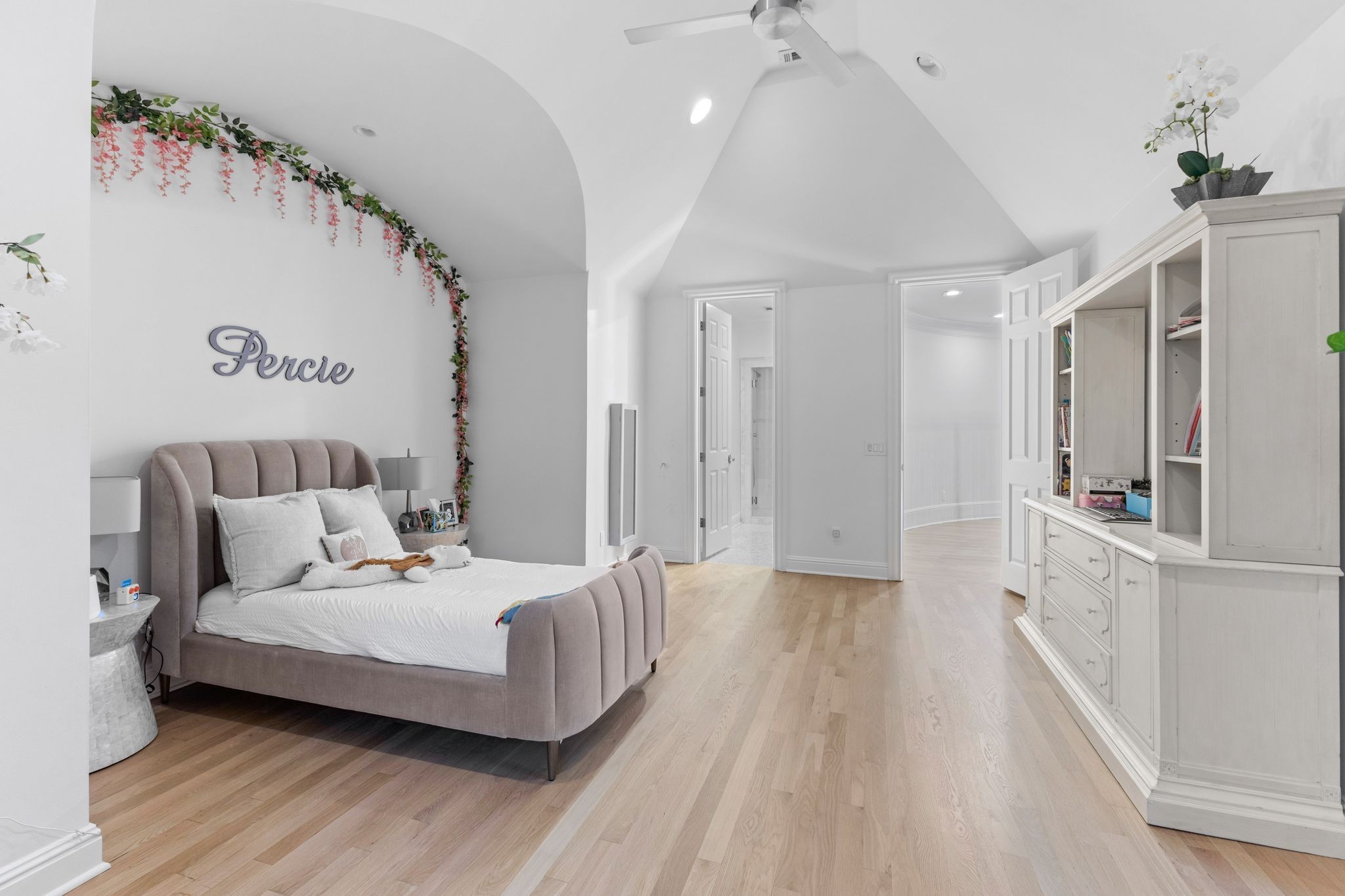 Bedroom with a mauve upholstered bed, vaulted ceiling, and large white built-in cabinet.