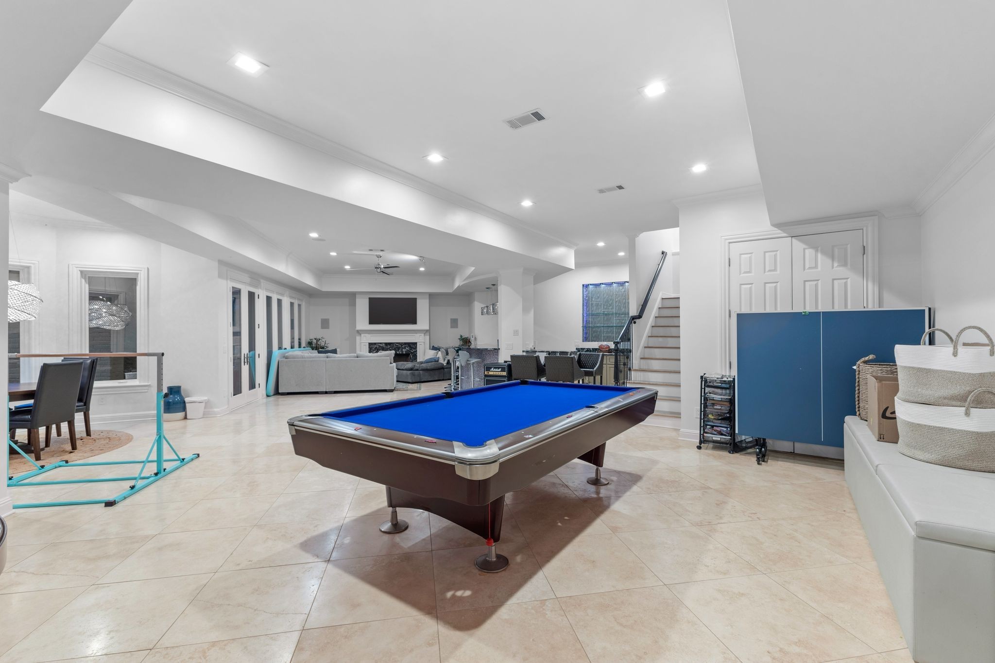 Recreation room with a blue-felt pool table, fireplace, and folded ping-pong table.