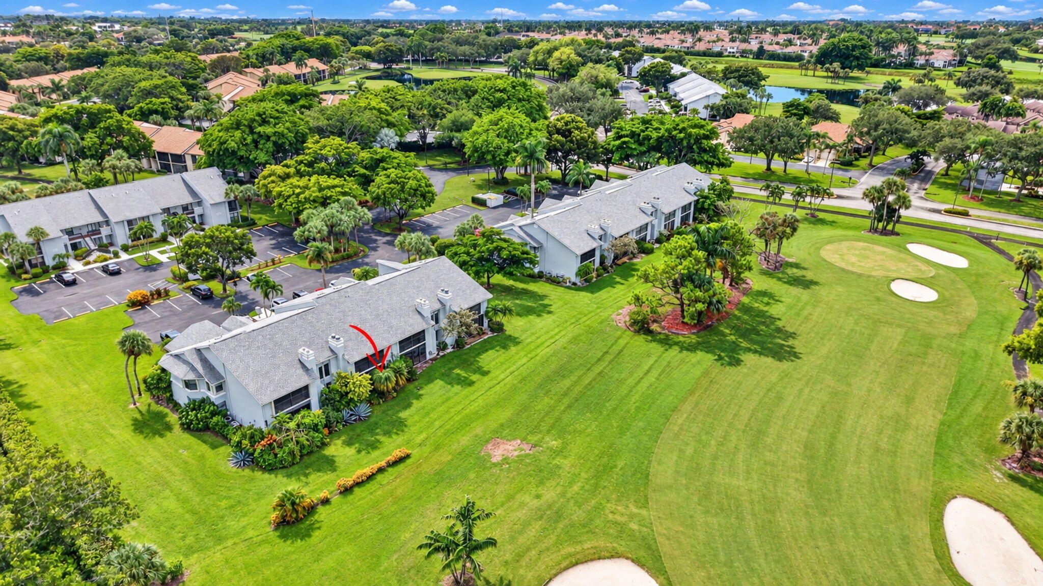 Aerial view of a residence beside a golf course, marked by a red arrow.