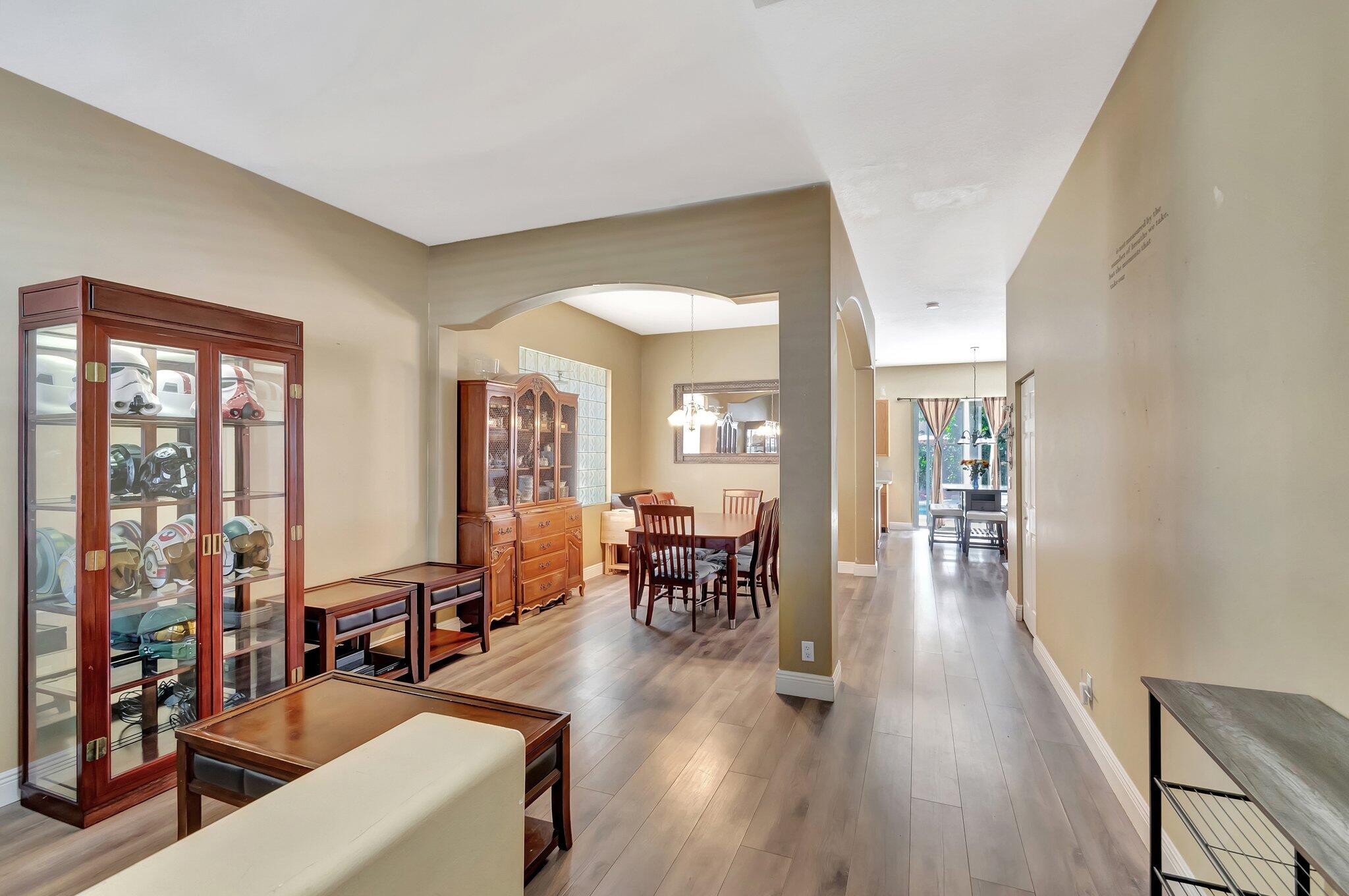 Dining area with wood furniture and helmet display cabinets beside a long hallway.