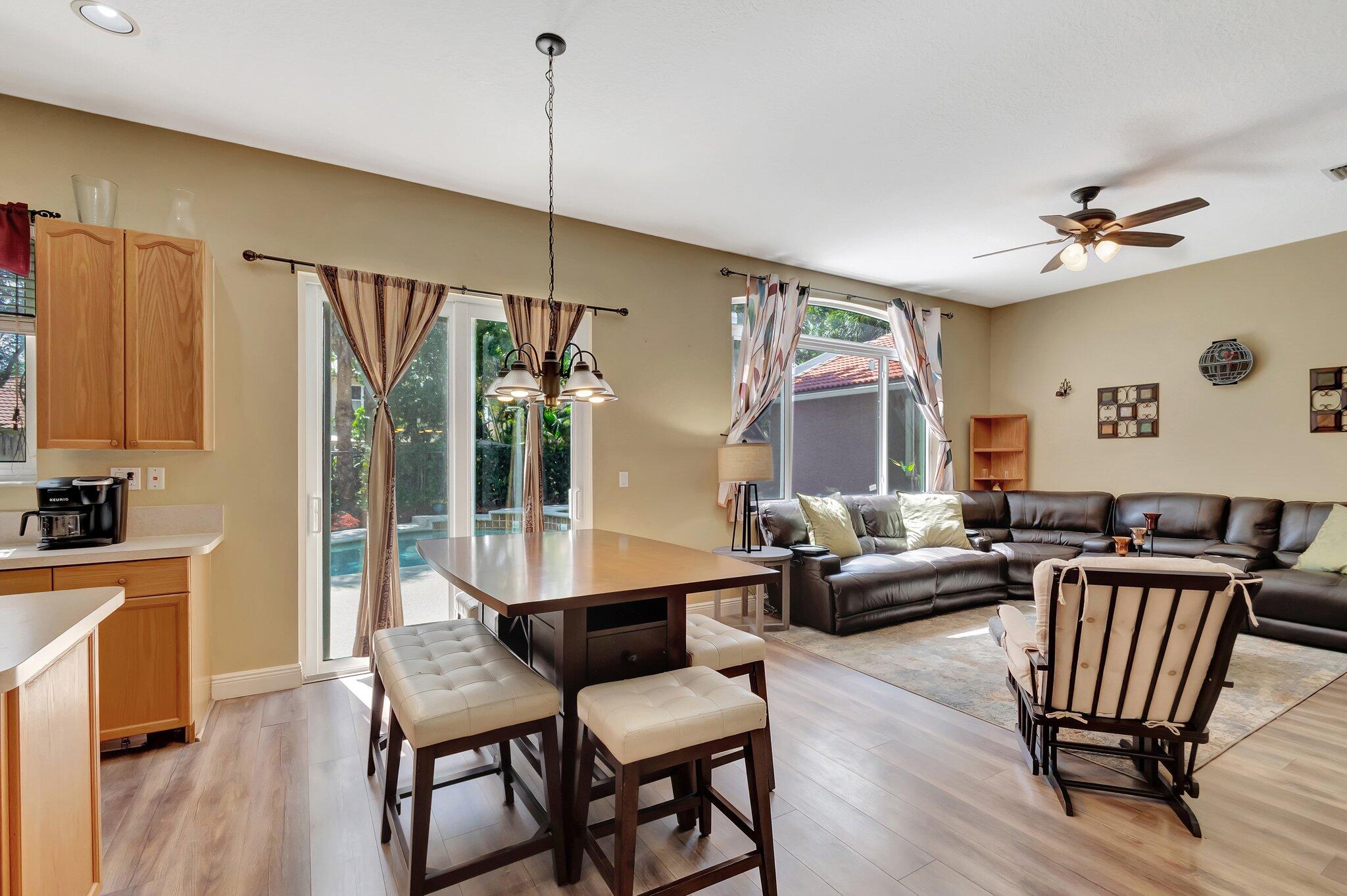 Open-plan living room with a dark sectional, dining table, and sliding glass doors.