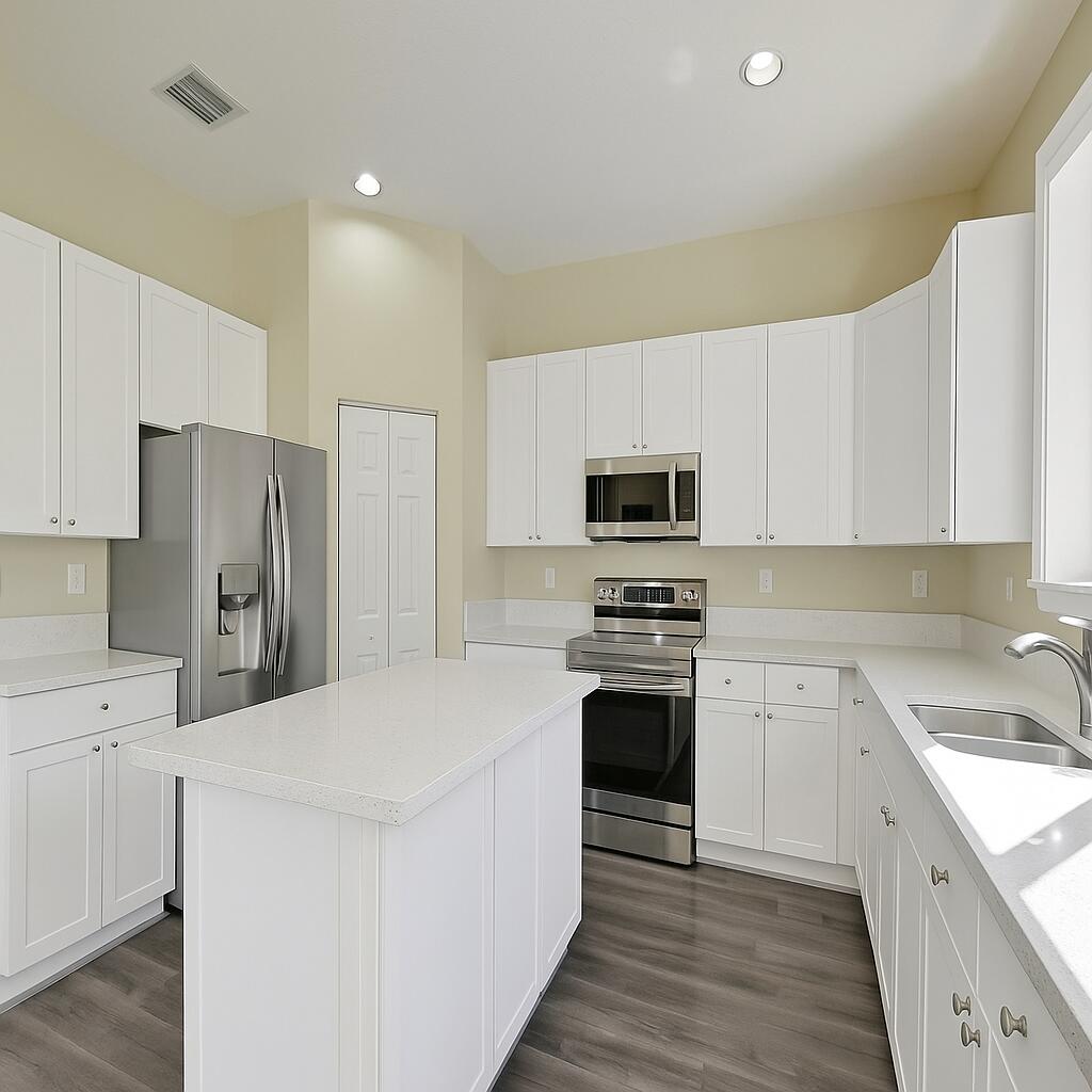 Modern kitchen with white cabinets, a large island, and stainless steel appliances.
