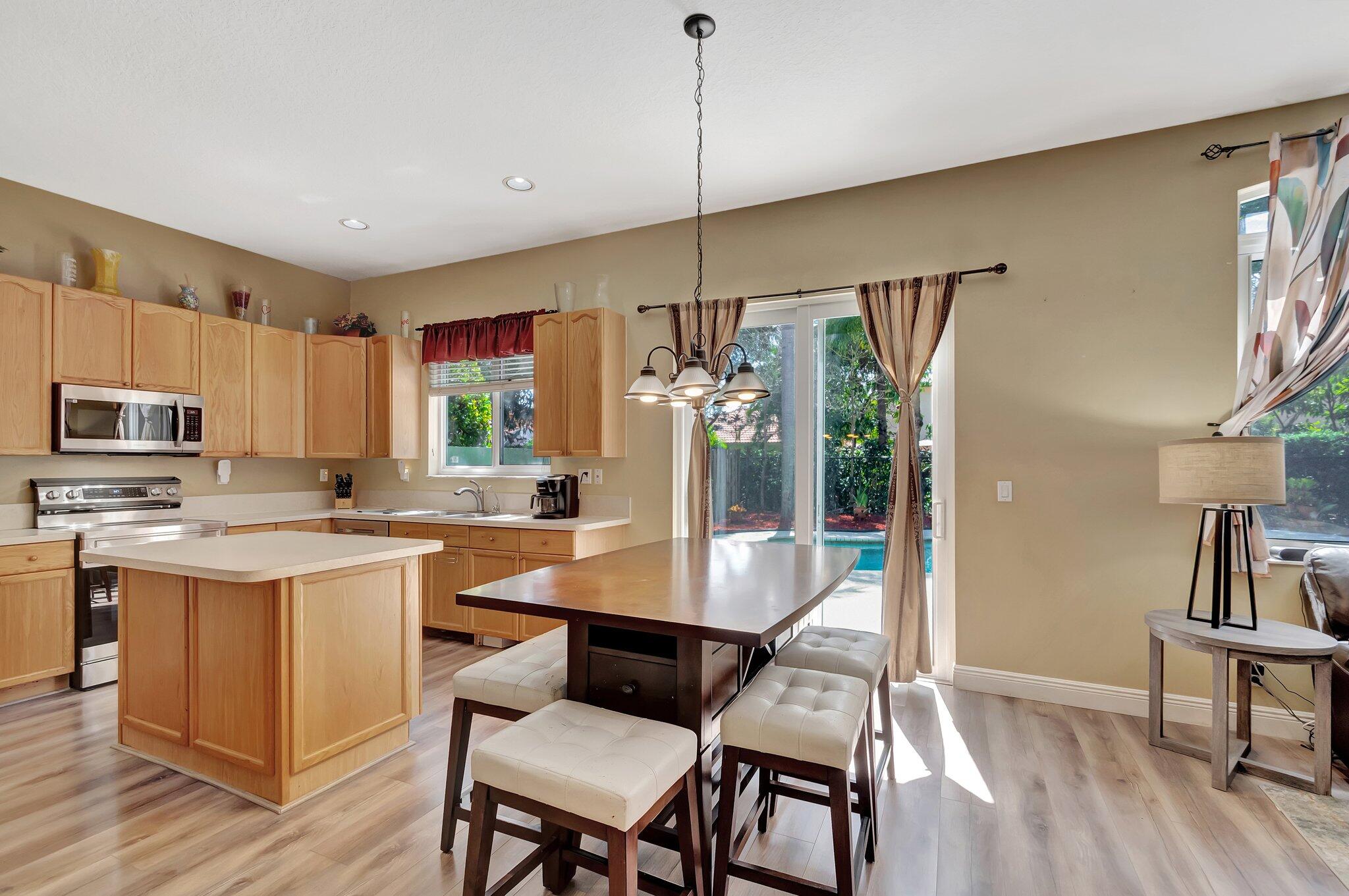 Kitchen and dining area with a wood-cabinet island and sliding doors overlooking a pool.
