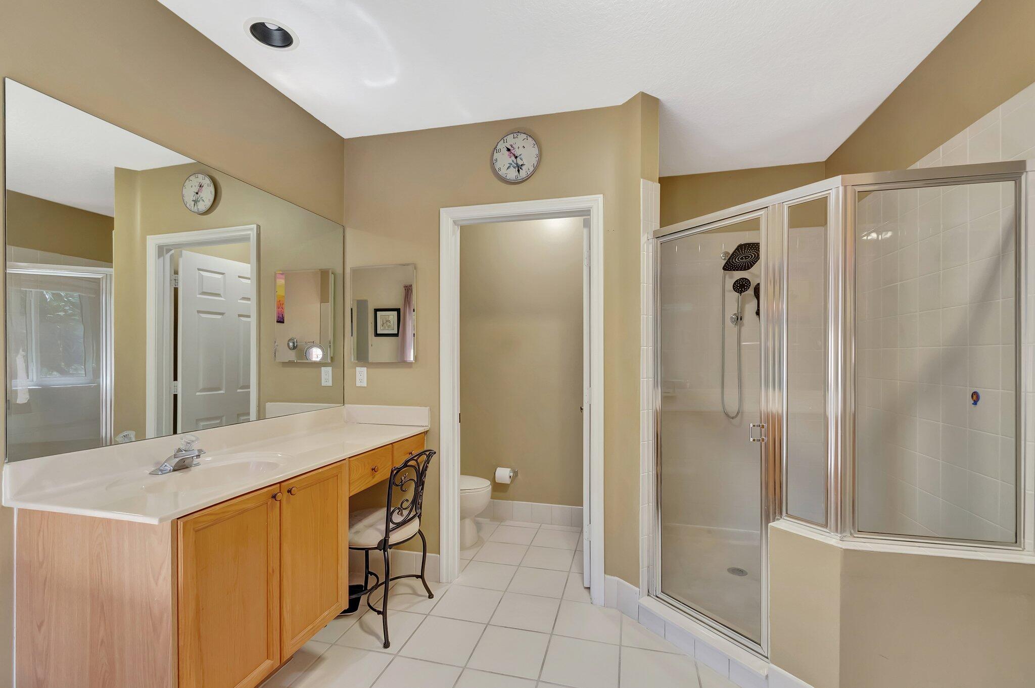 Bathroom with a long mirrored vanity, glass shower enclosure, and separate tiled tub area.