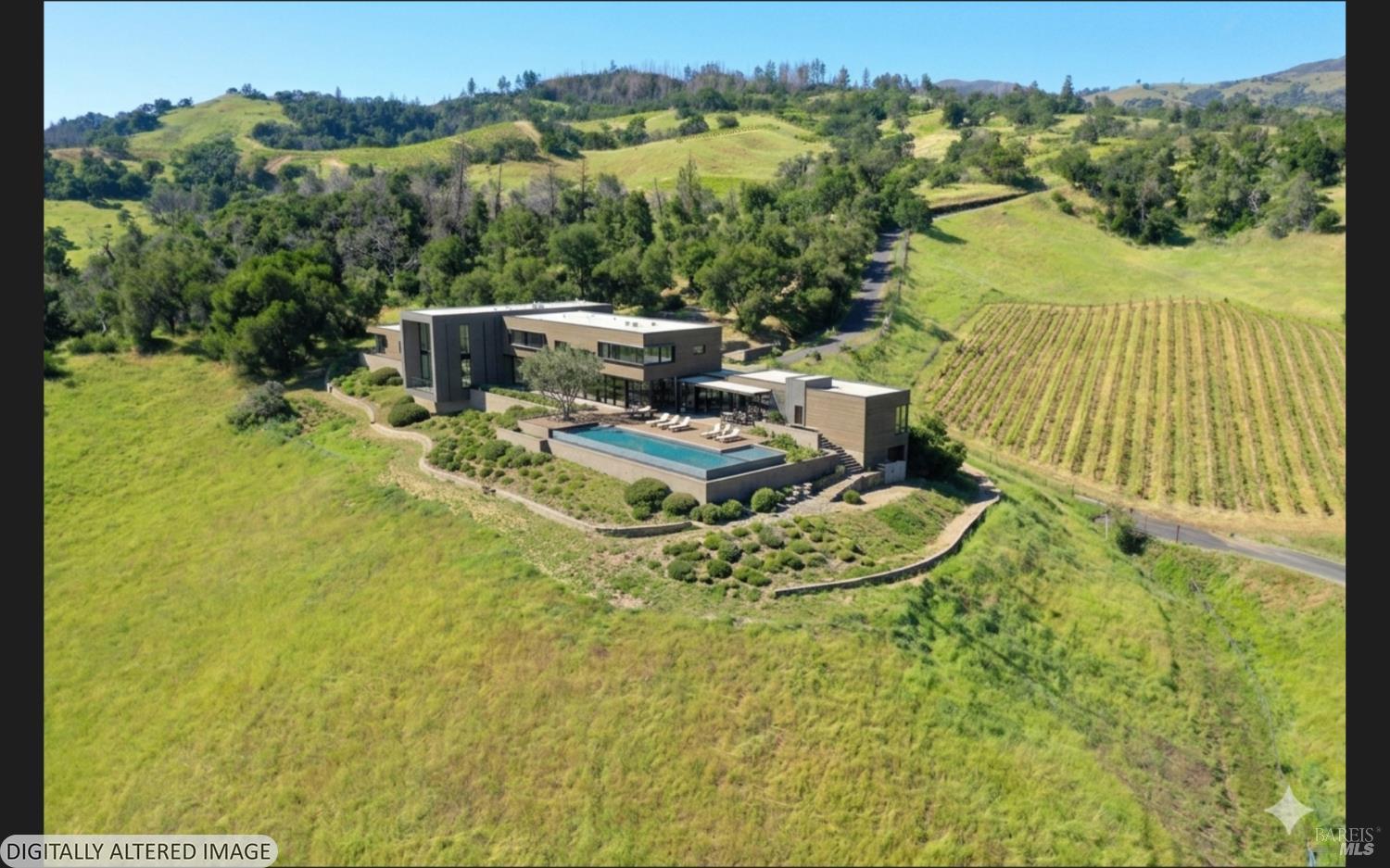 Modern home with a long pool amid rolling hills and vineyard rows.
