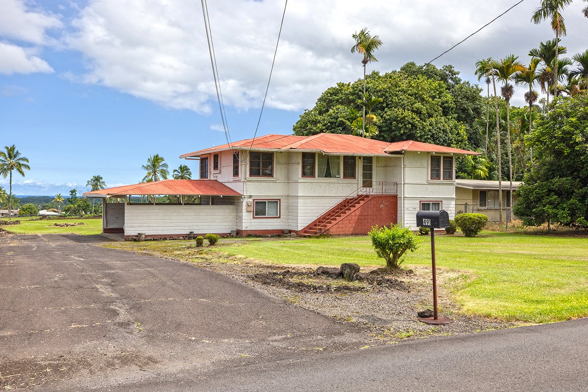 Two-story white house with red roof, exterior staircase, tropical palms, and mailbox 491.