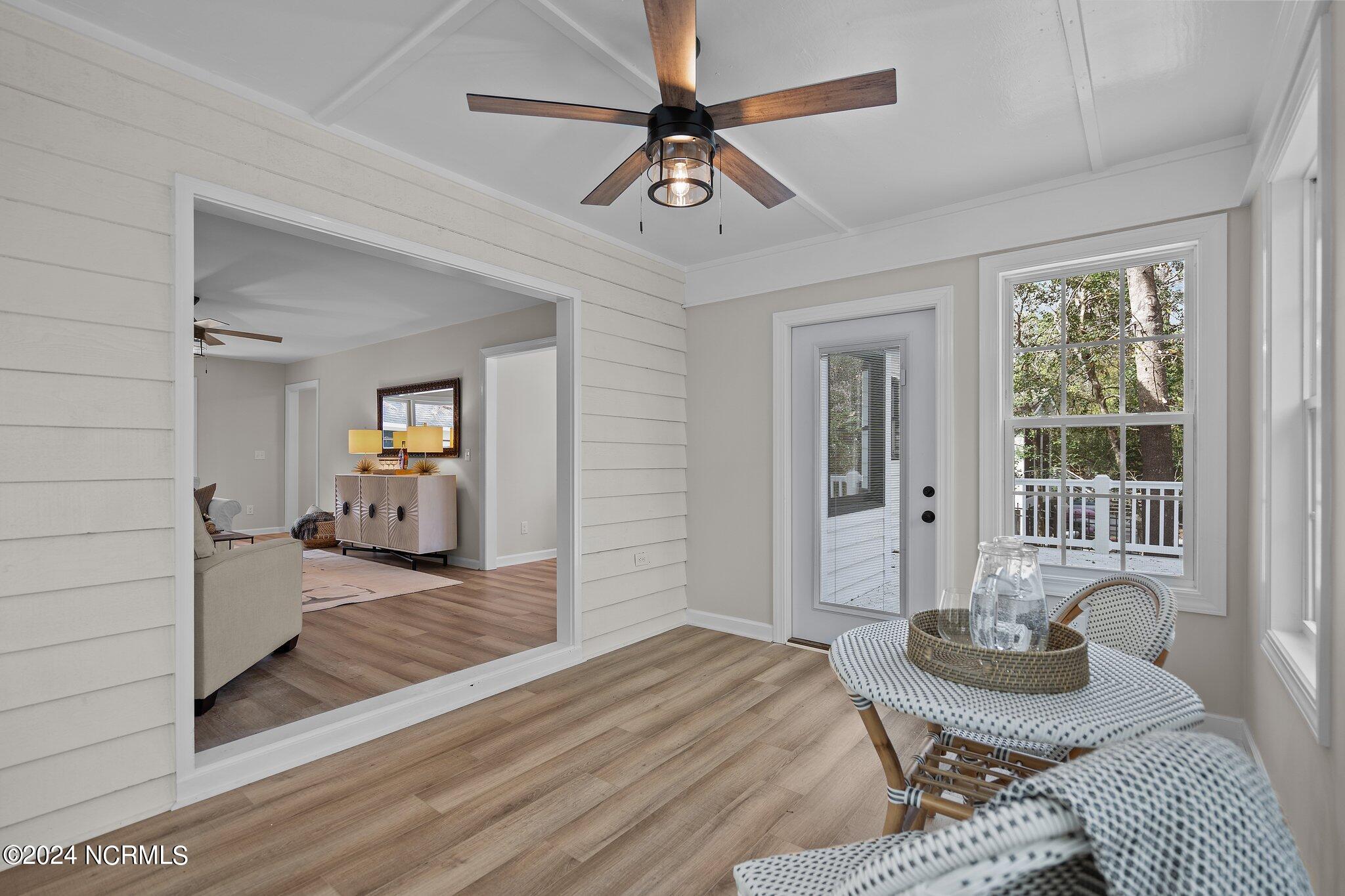 Sunroom with woven seating, a ceiling fan, and a view of the deck and trees.