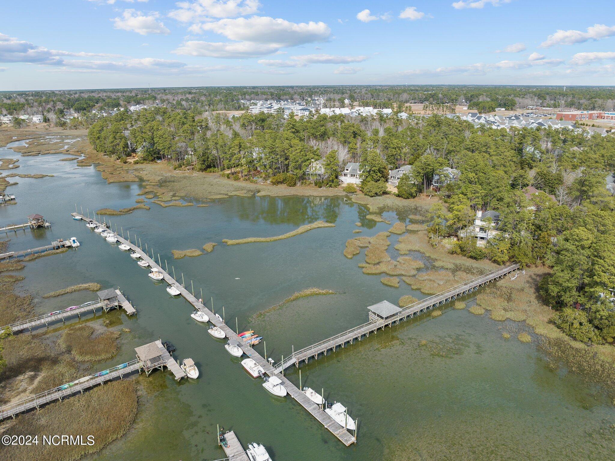 Aerial view of a creek and marsh, with boats along long docks and homes among shoreline trees.