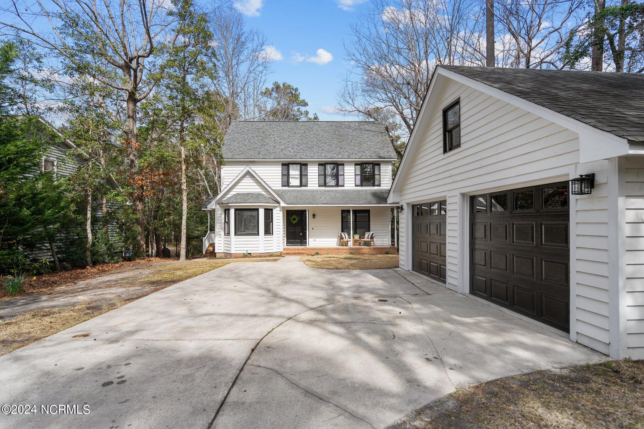 White two-story house with a large dark-doored garage and a wide concrete driveway.