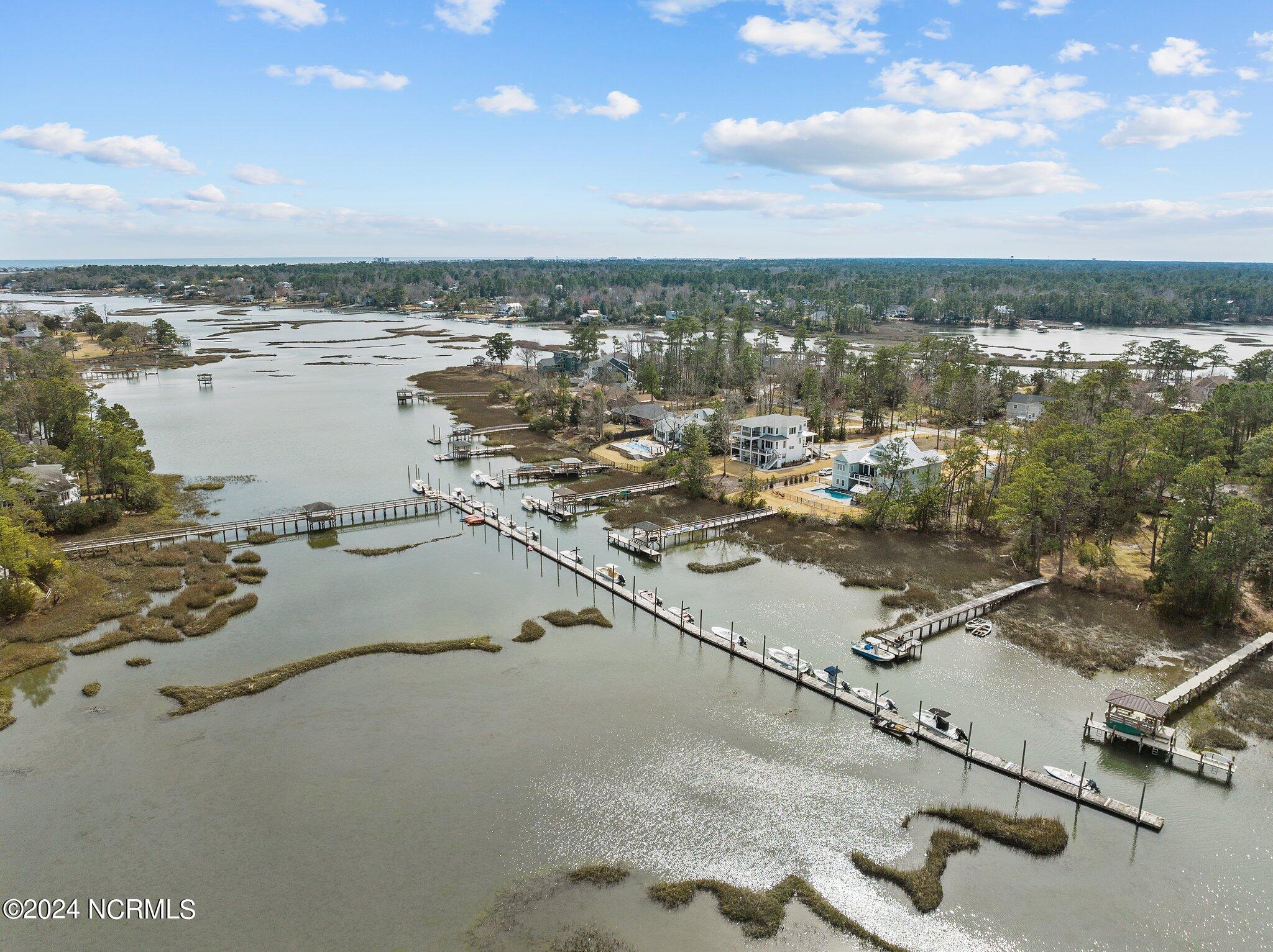 Aerial view of waterfront homes and long docks extending into a marsh-lined creek.