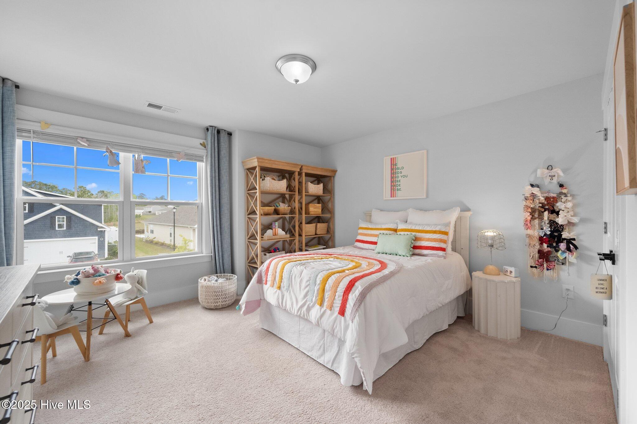 Furnished bedroom with colorful striped bedding, wooden shelving, and a large window.