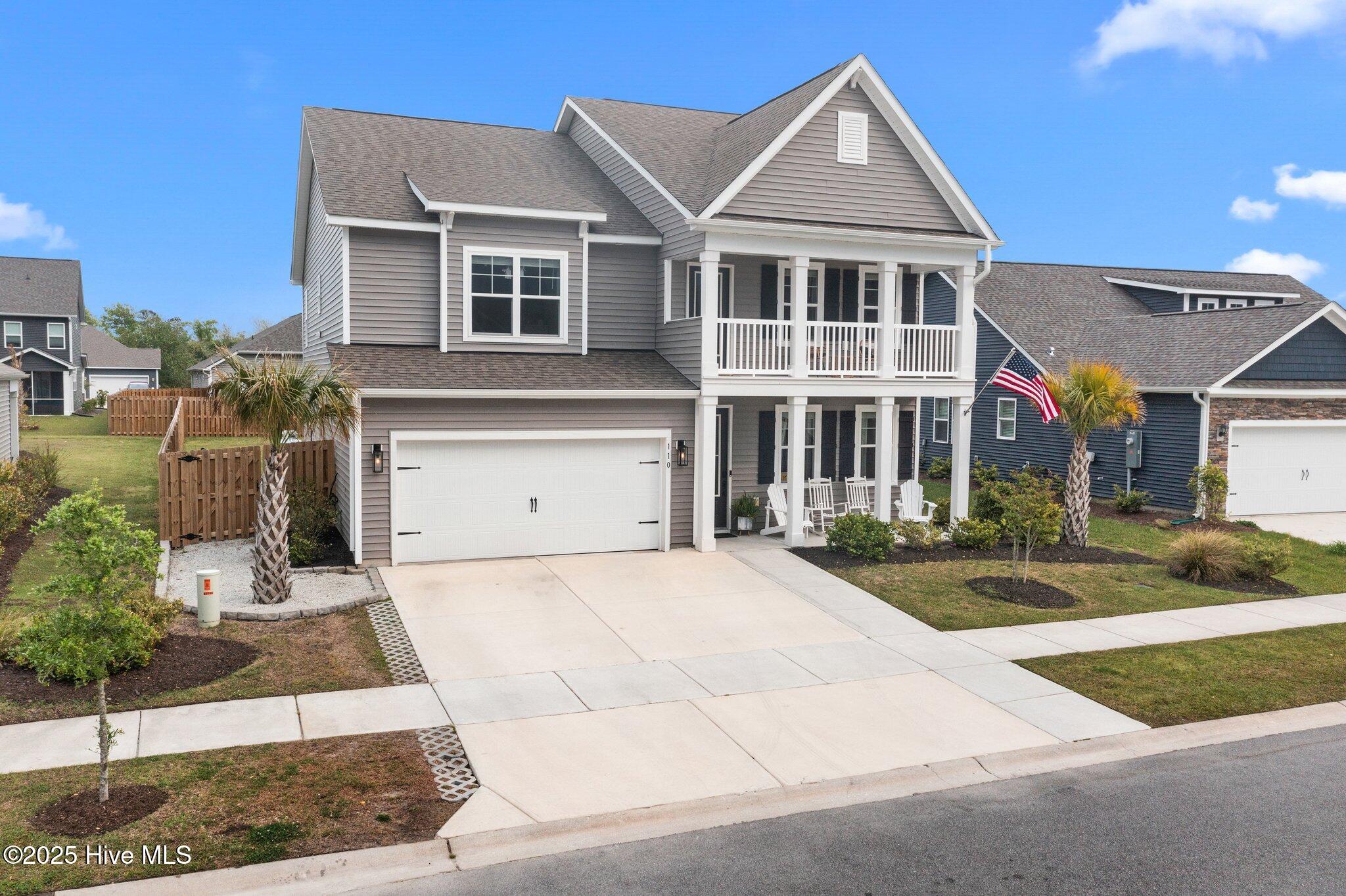Gray two-story home with white trim, double garage, covered porches, and palm trees.