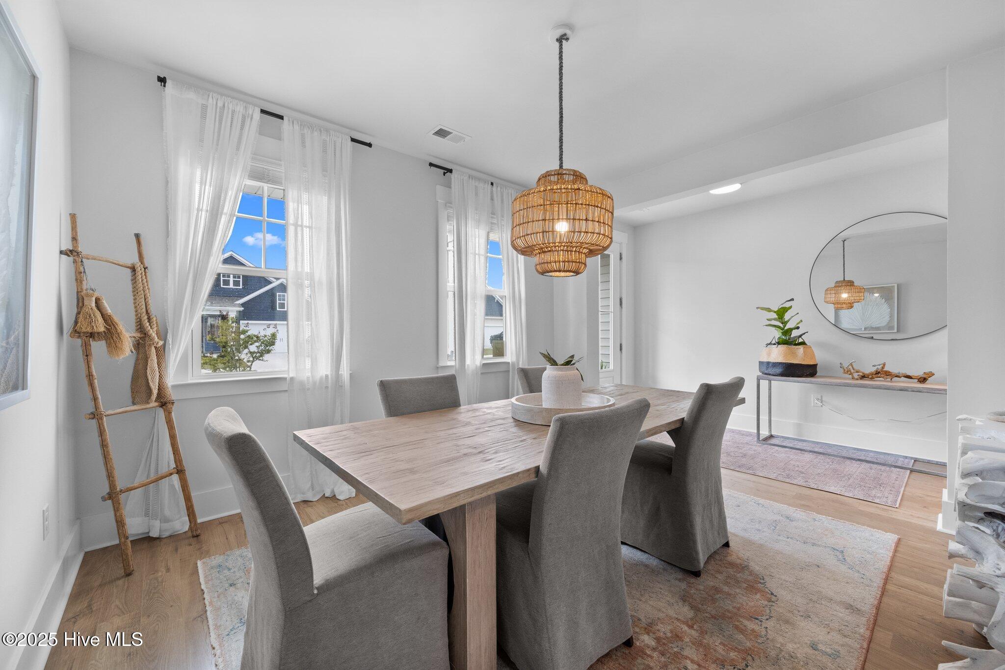 Staged dining room with a wood table, gray chairs, and a woven pendant light.