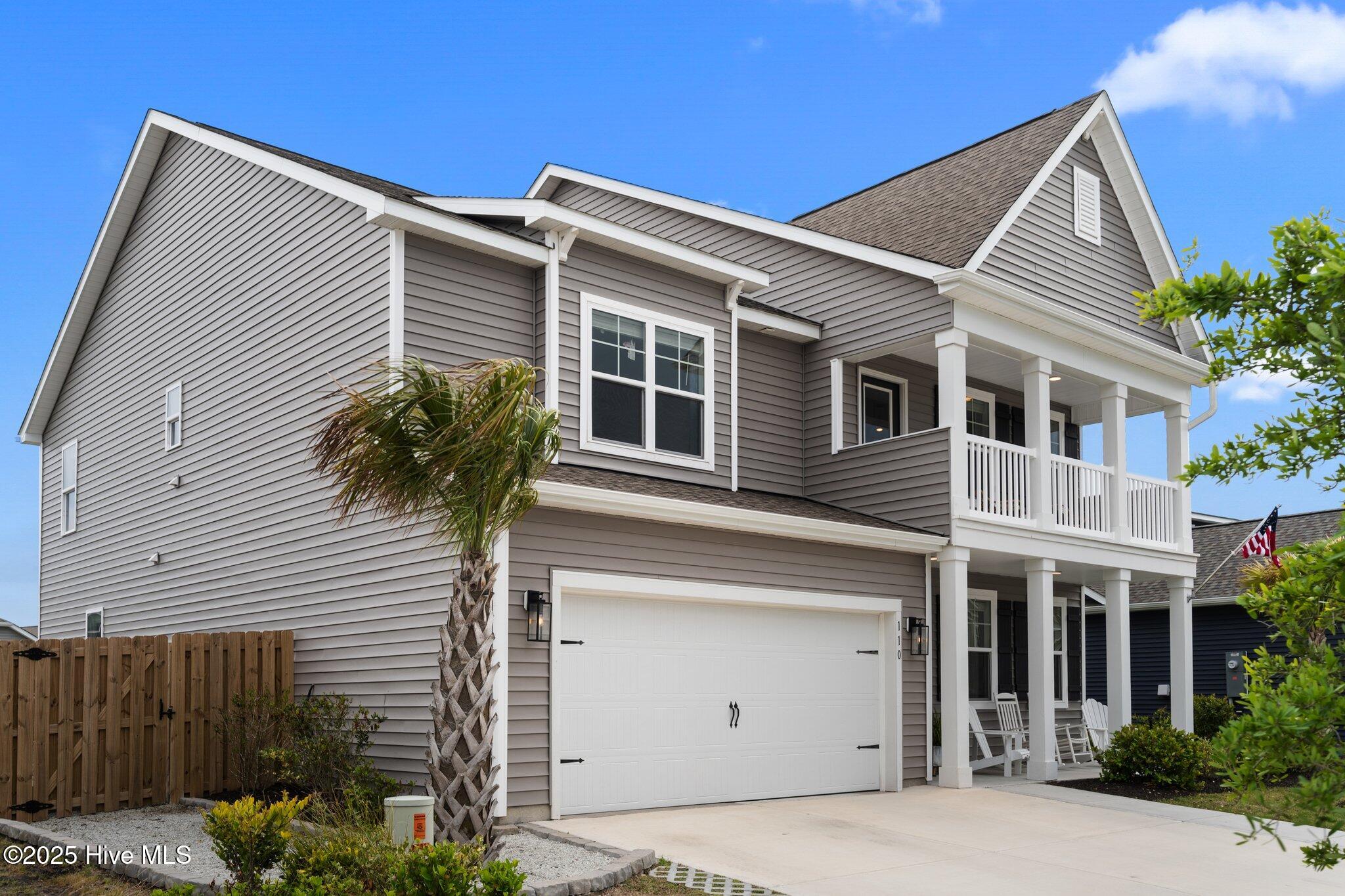 Two-story gray home with a white double garage and covered porch, framed by a palm tree.
