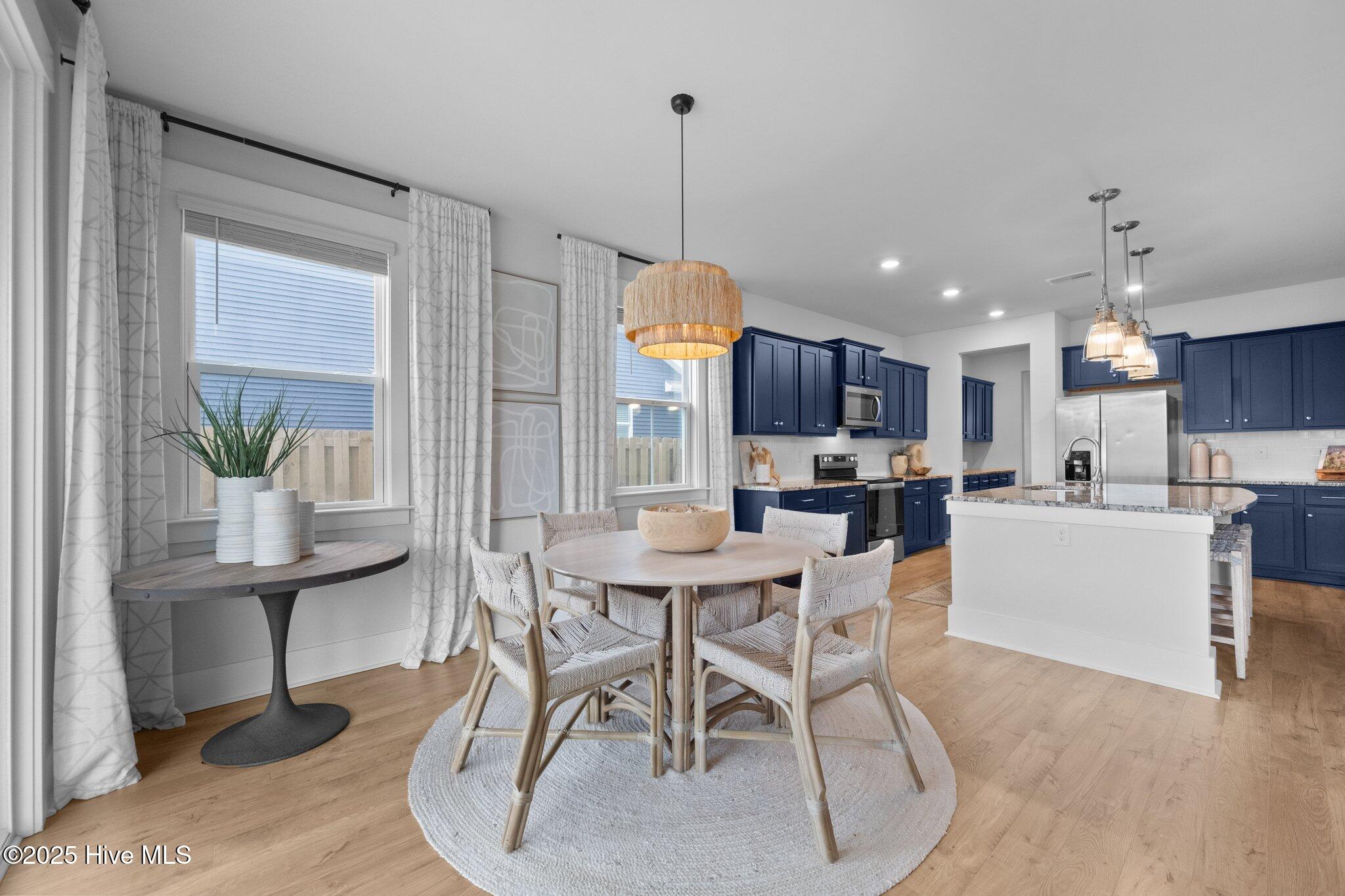 Open-plan kitchen and dining area with navy cabinets, a white island, and a round table by the windows.