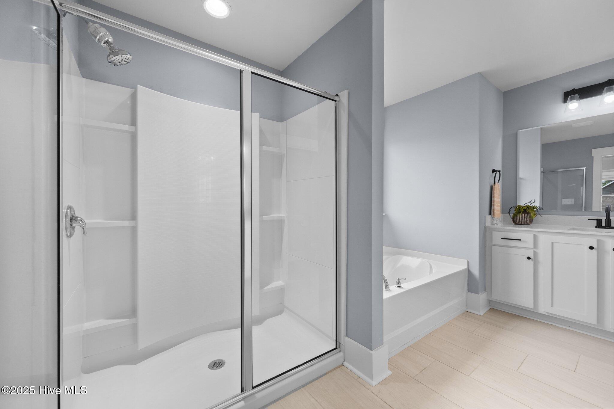 Bathroom with a glass-enclosed walk-in shower, soaking tub, and white vanity.