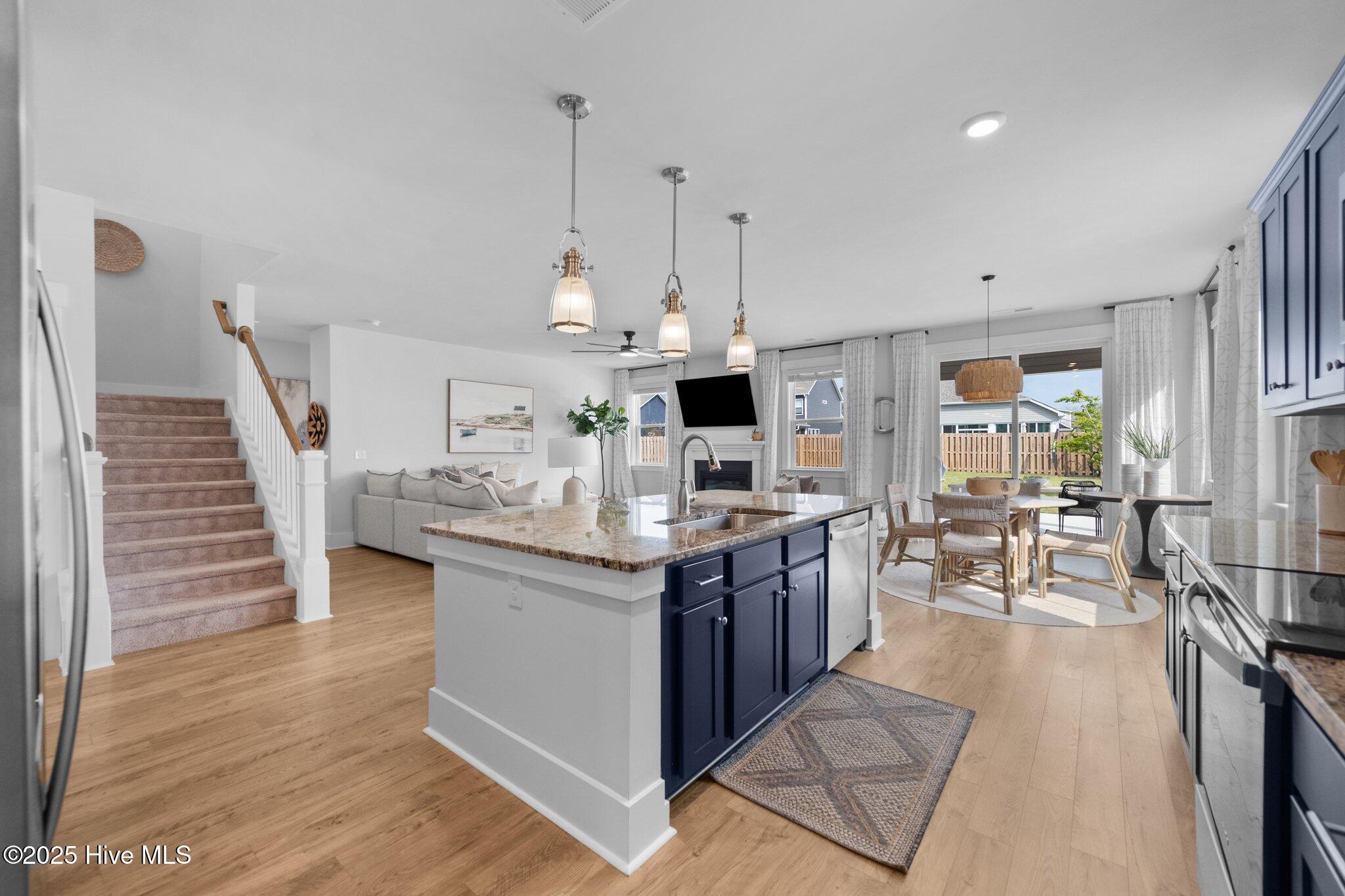 Open-concept kitchen with a large navy island, stone countertop, and adjoining dining and living areas.