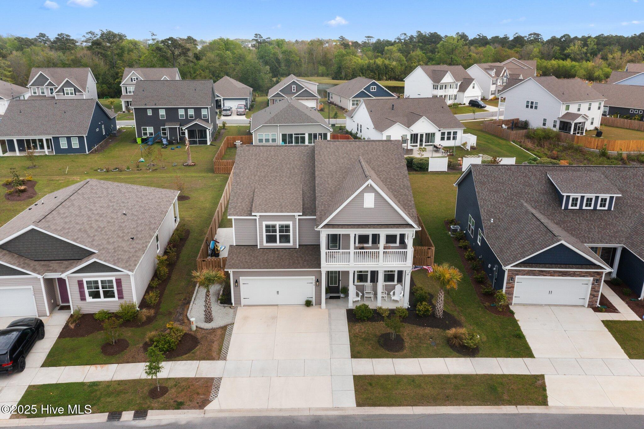 Aerial view of a gray two-story home with a balcony, front porch, and attached garage.