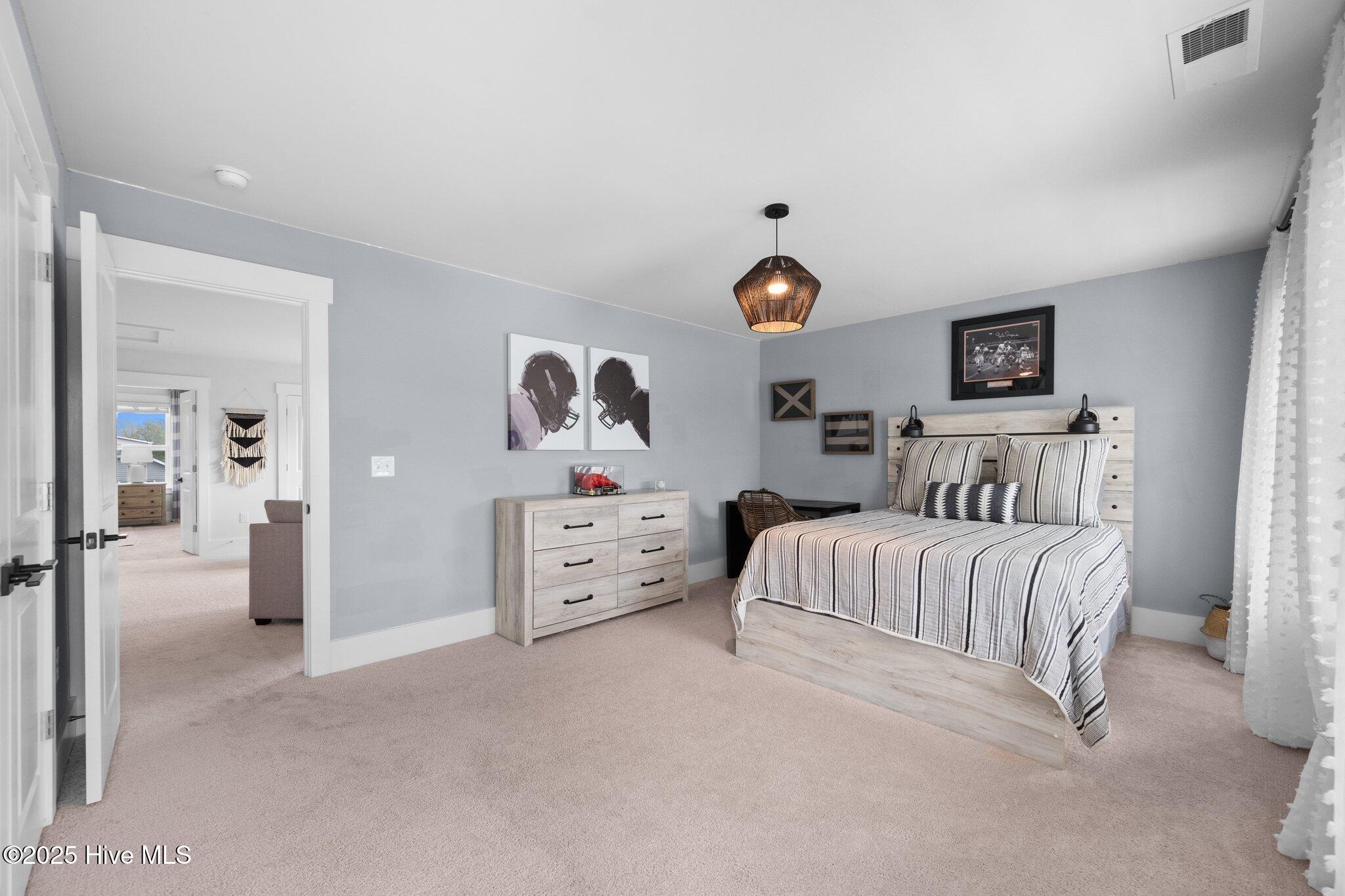 Furnished bedroom with striped bedding, light wood furniture, and football-themed wall art.