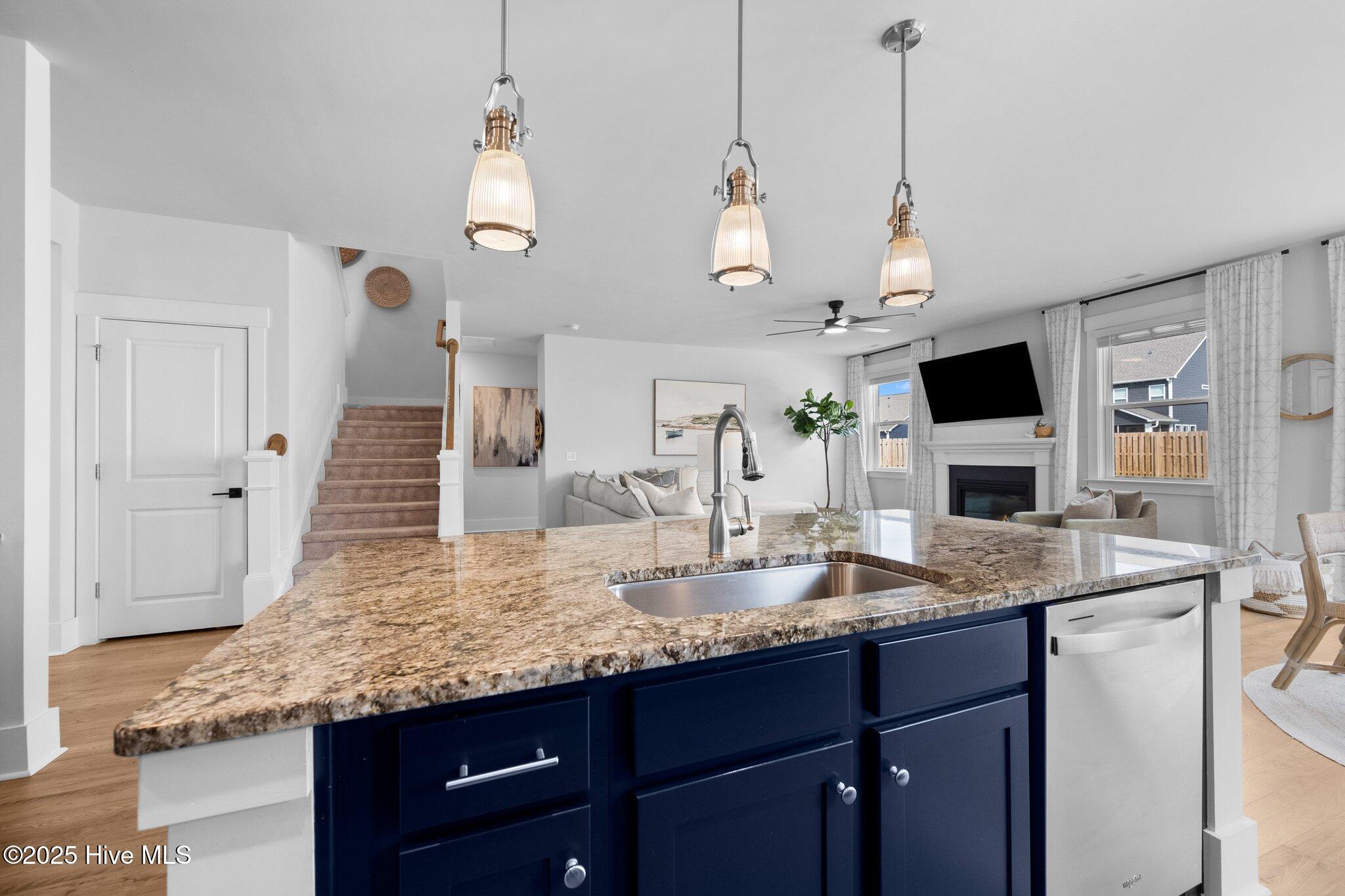 Kitchen with a granite island, navy cabinets, and an open living area with a fireplace.