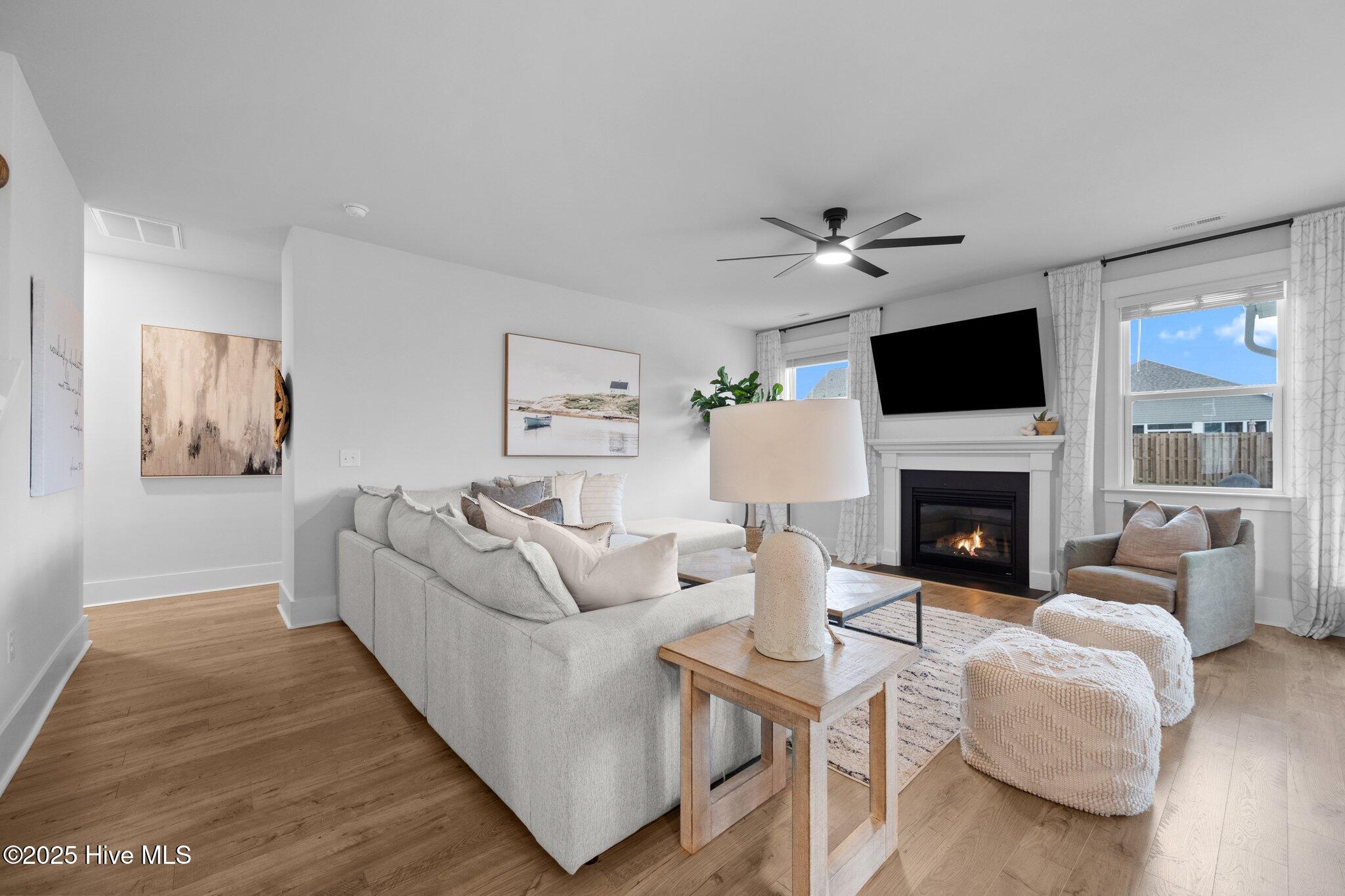 Furnished living room with a large sectional, fireplace, and television above the mantel.