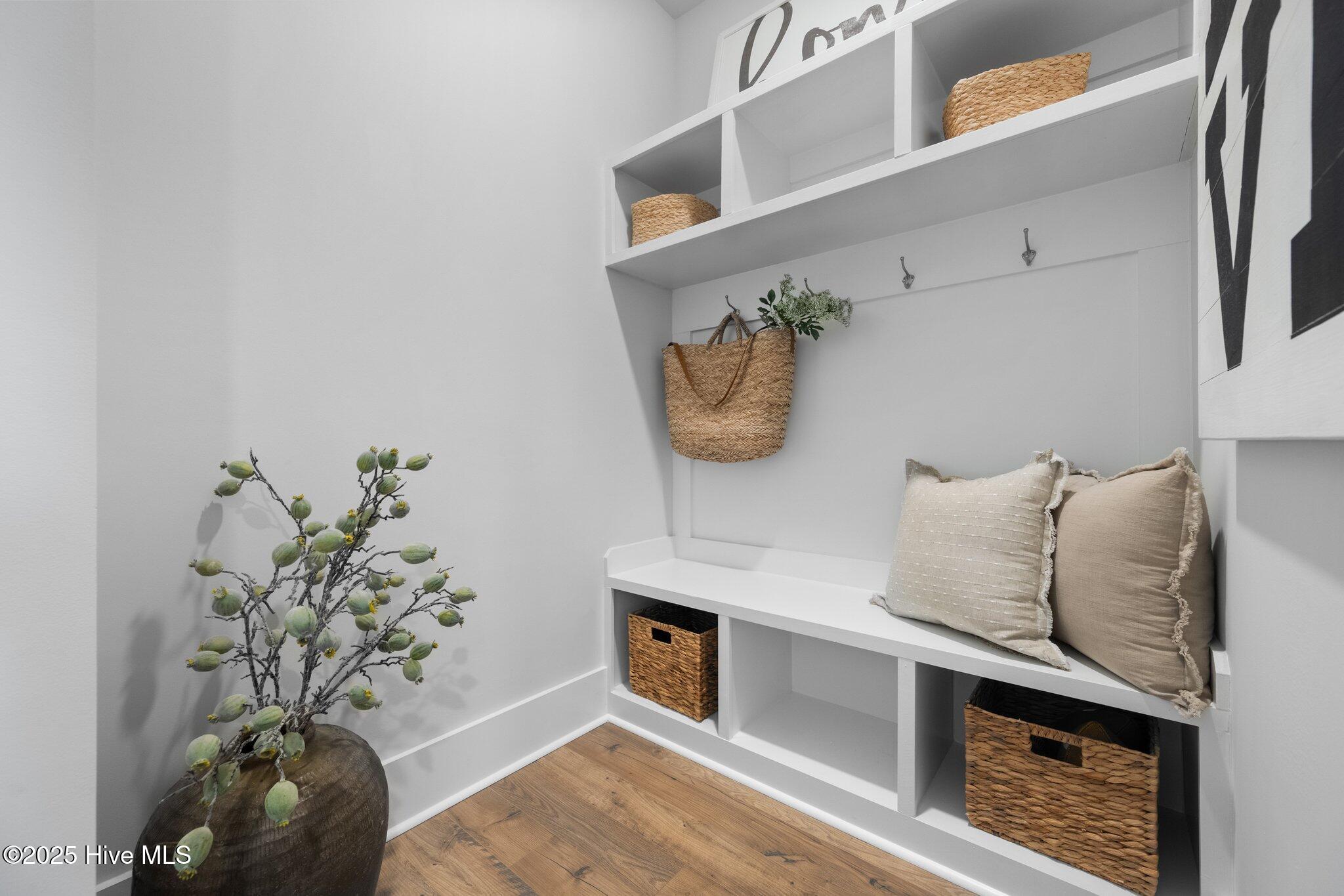 Entryway with a white built-in bench, cubbies, woven baskets, and neutral pillows.