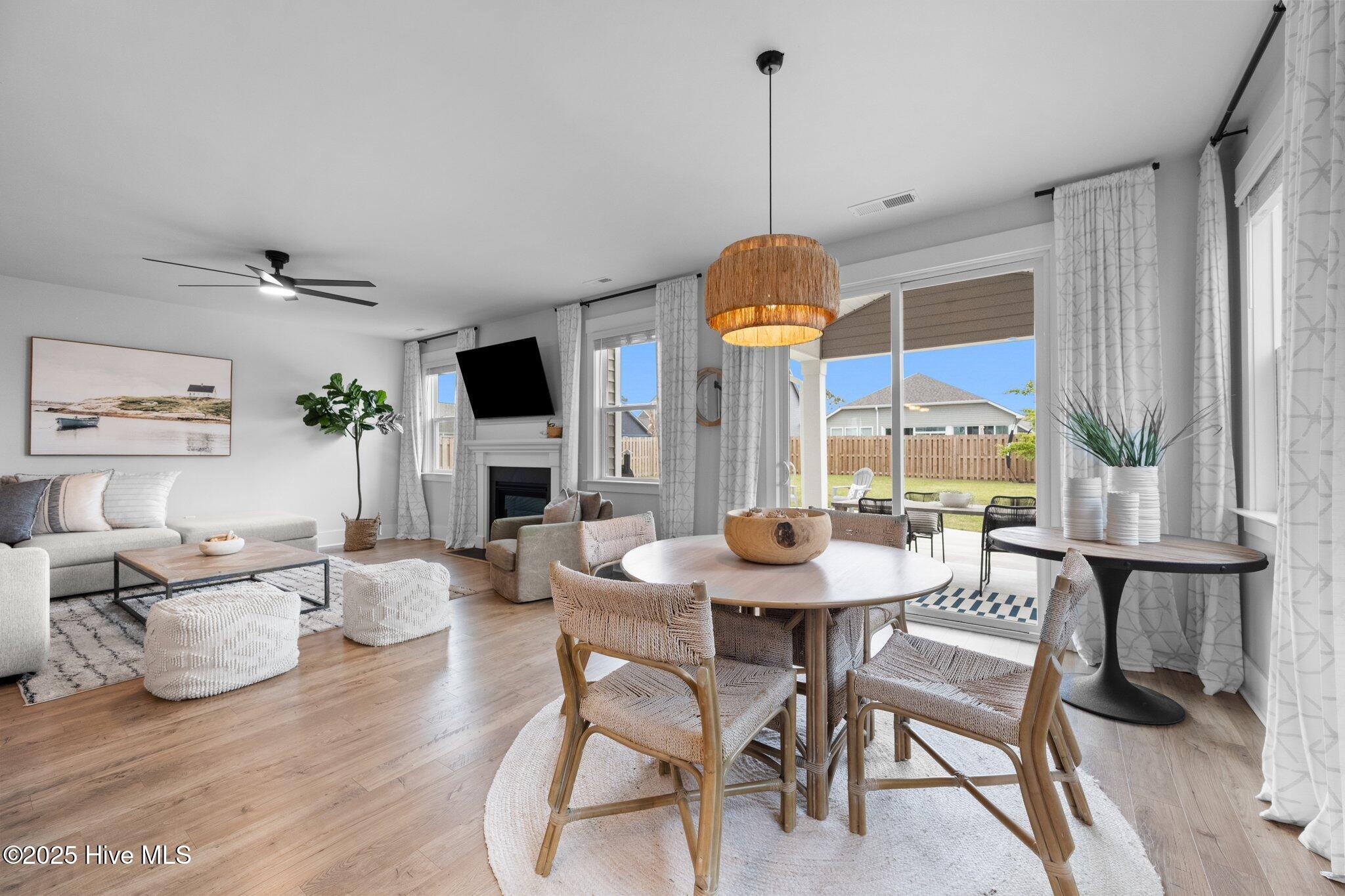 Open living and dining room with a fireplace and sliding doors to a fenced backyard patio.