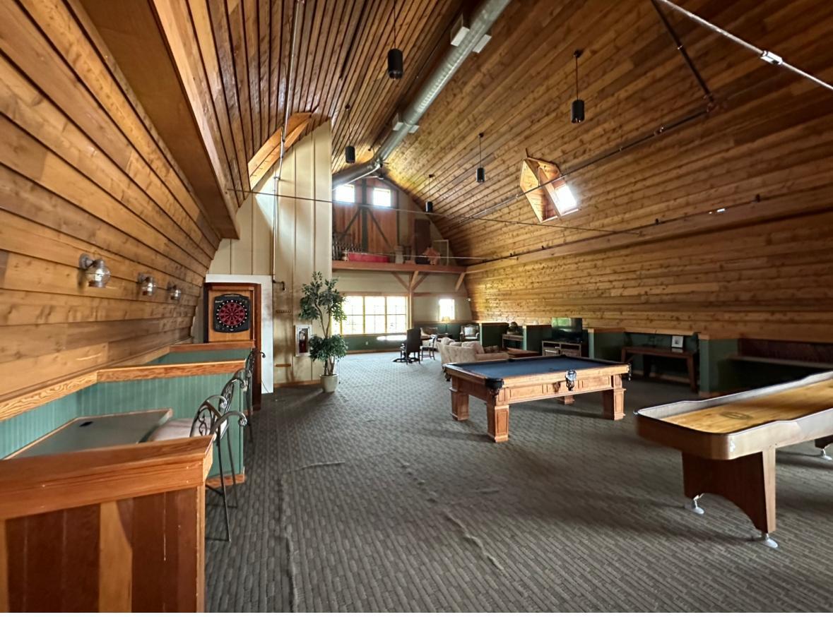 Game room with a vaulted wood ceiling, pool table, shuffleboard table and dartboard.