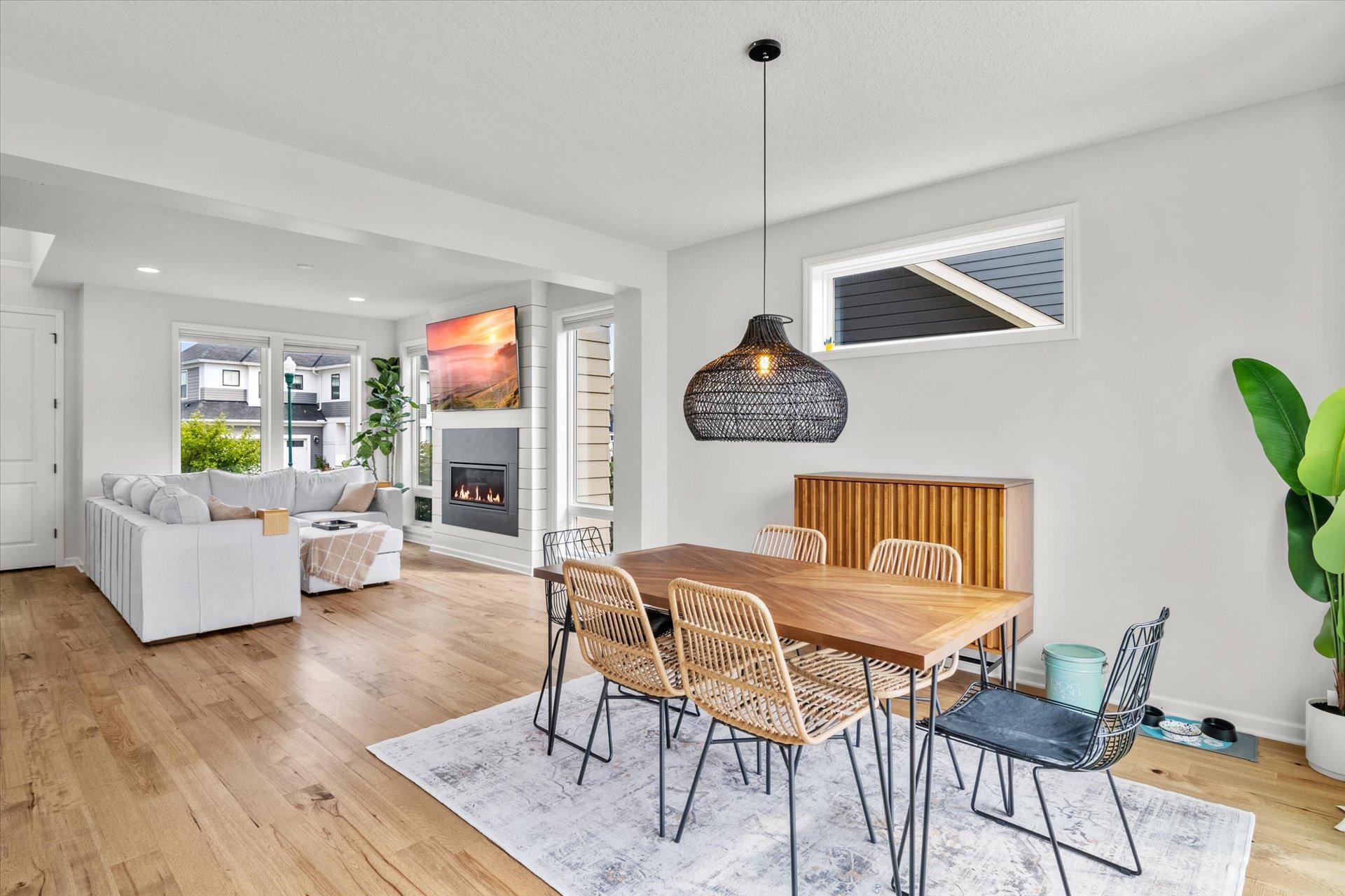 Open-plan living and dining room with a white sectional, wood table, and modern fireplace.