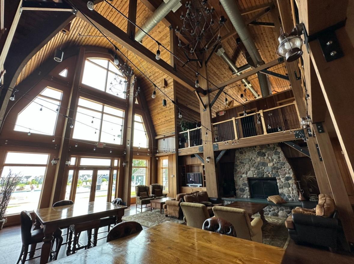 Furnished great room with a vaulted wood ceiling, exposed beams, loft, and stone fireplace.