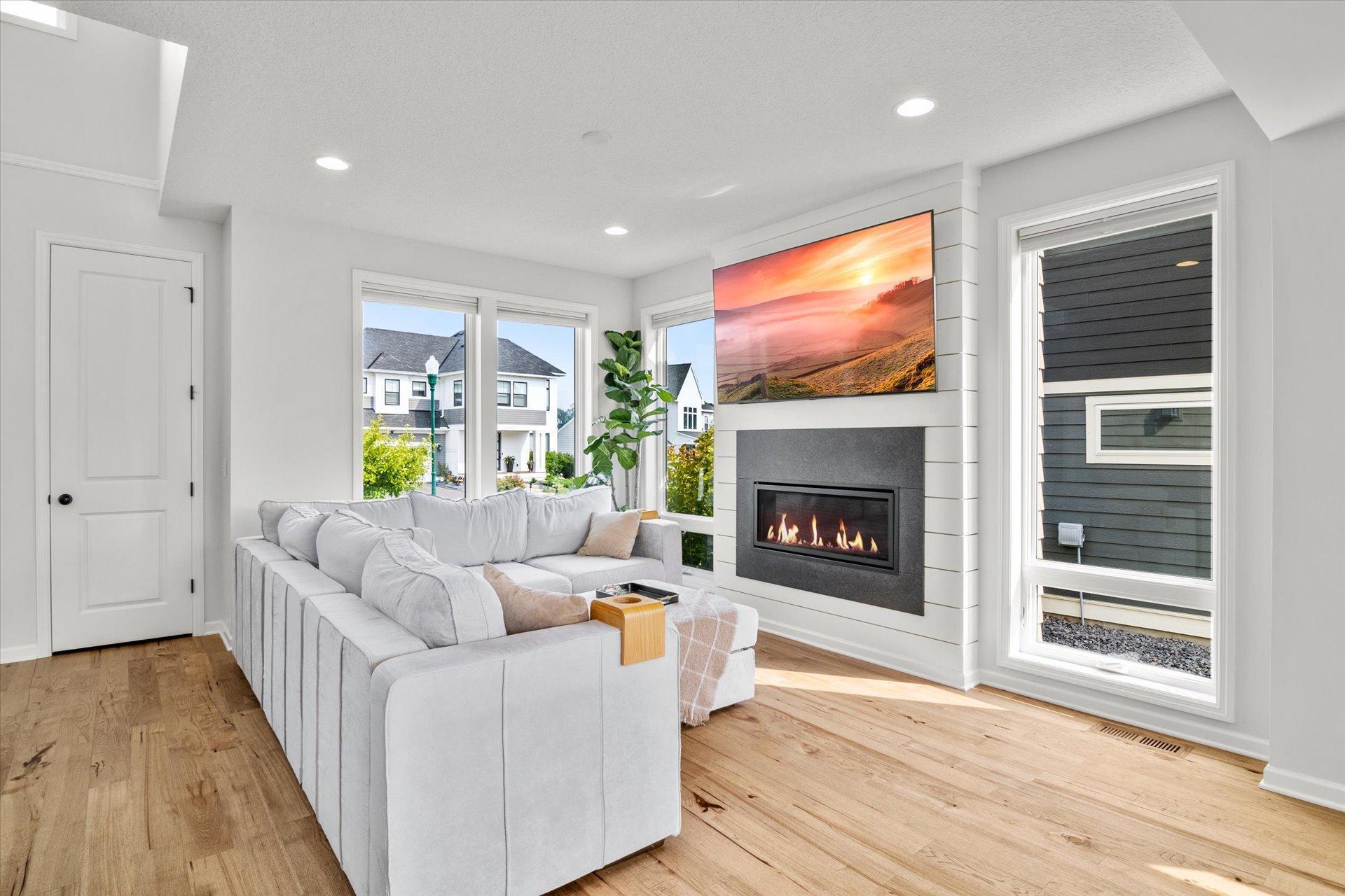 Living room with a large gray sectional, modern fireplace, and light wood floors.