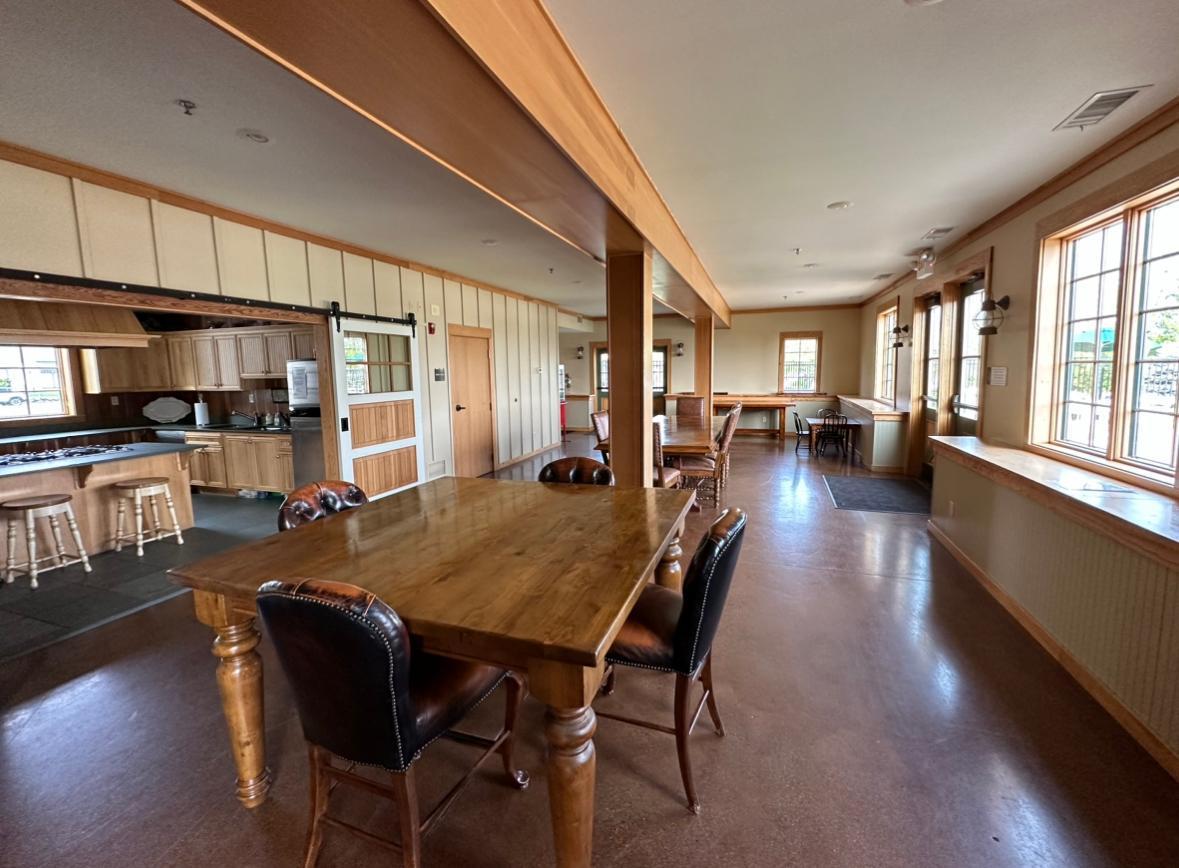 Kitchen and dining area with wood cabinetry, a large table, bar seating, and tall windows.