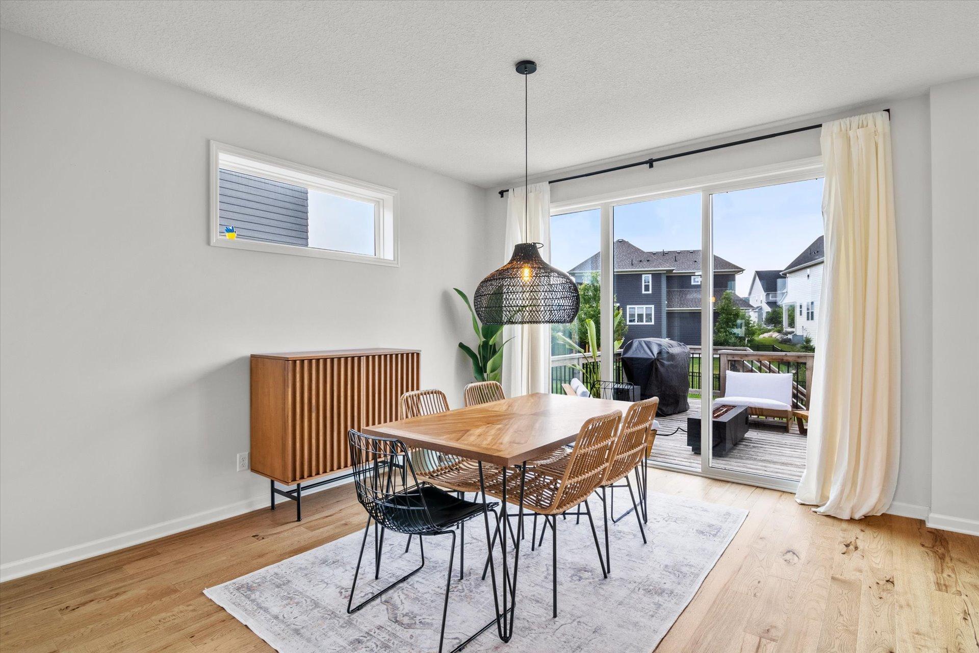 Dining room with a wooden table and woven chairs beside sliding doors to a deck.