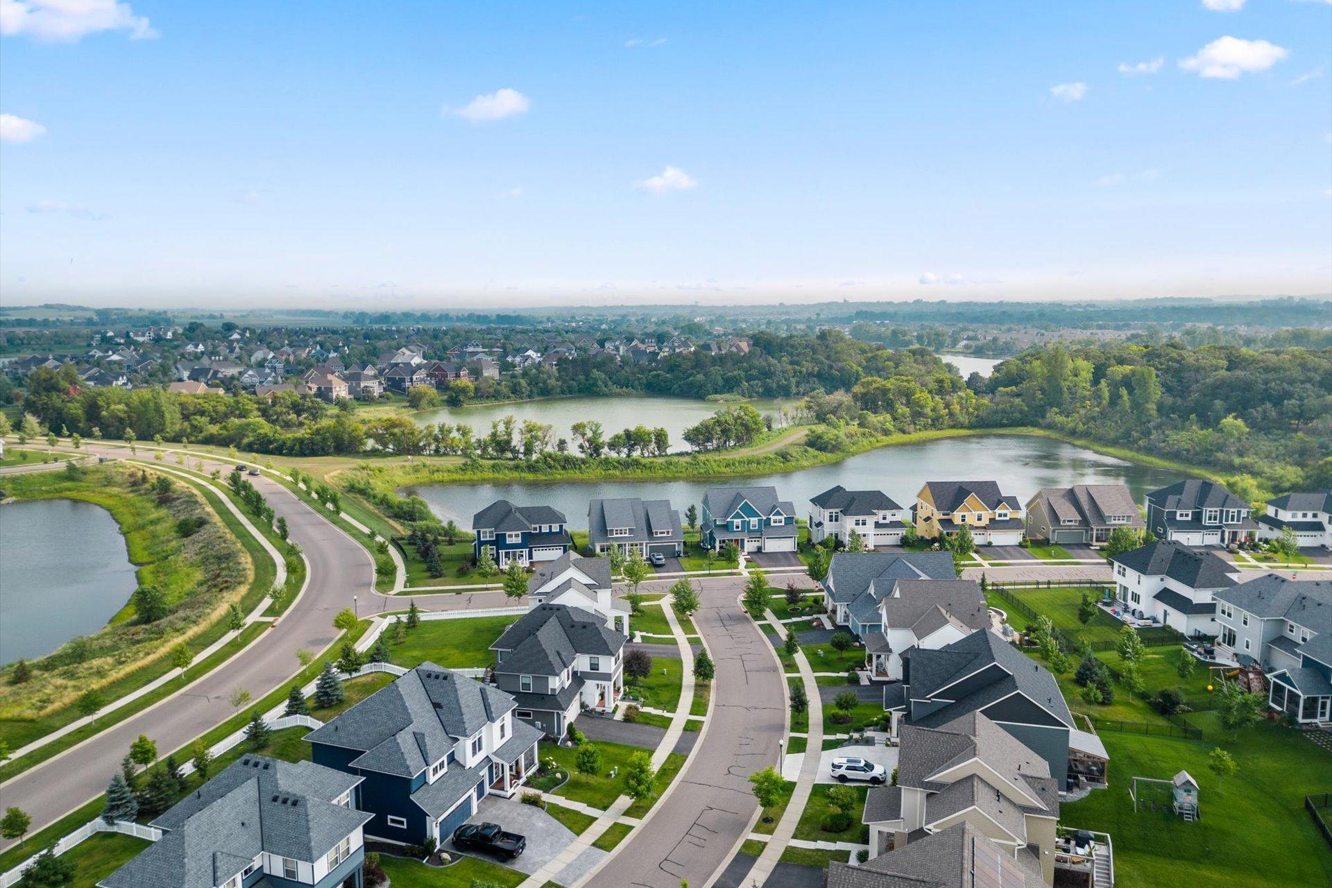 Aerial view of a lakeside neighborhood with homes, curving streets, and tree-lined water.