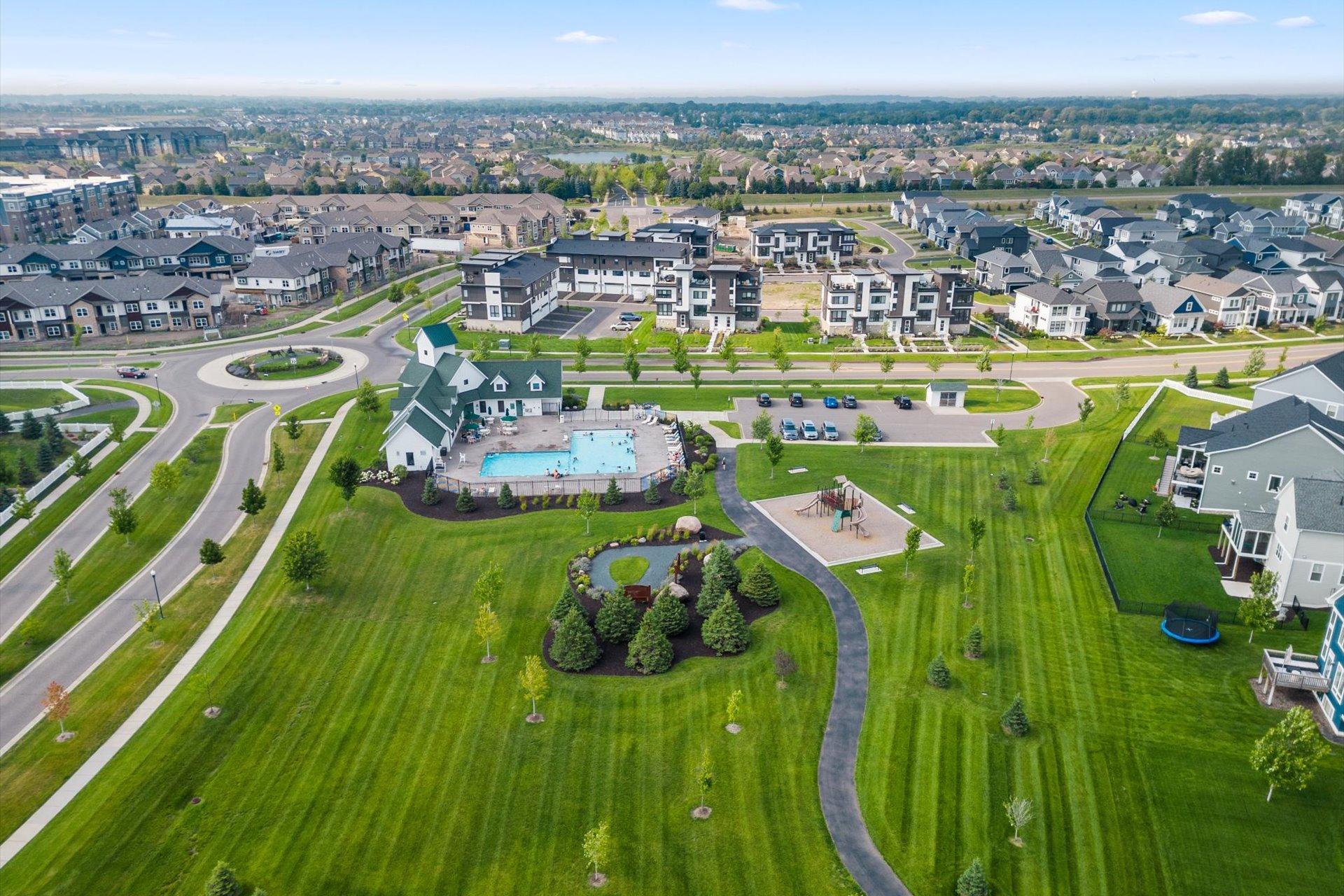 Aerial view of a residential community with a swimming pool, playground, and landscaped walking paths.